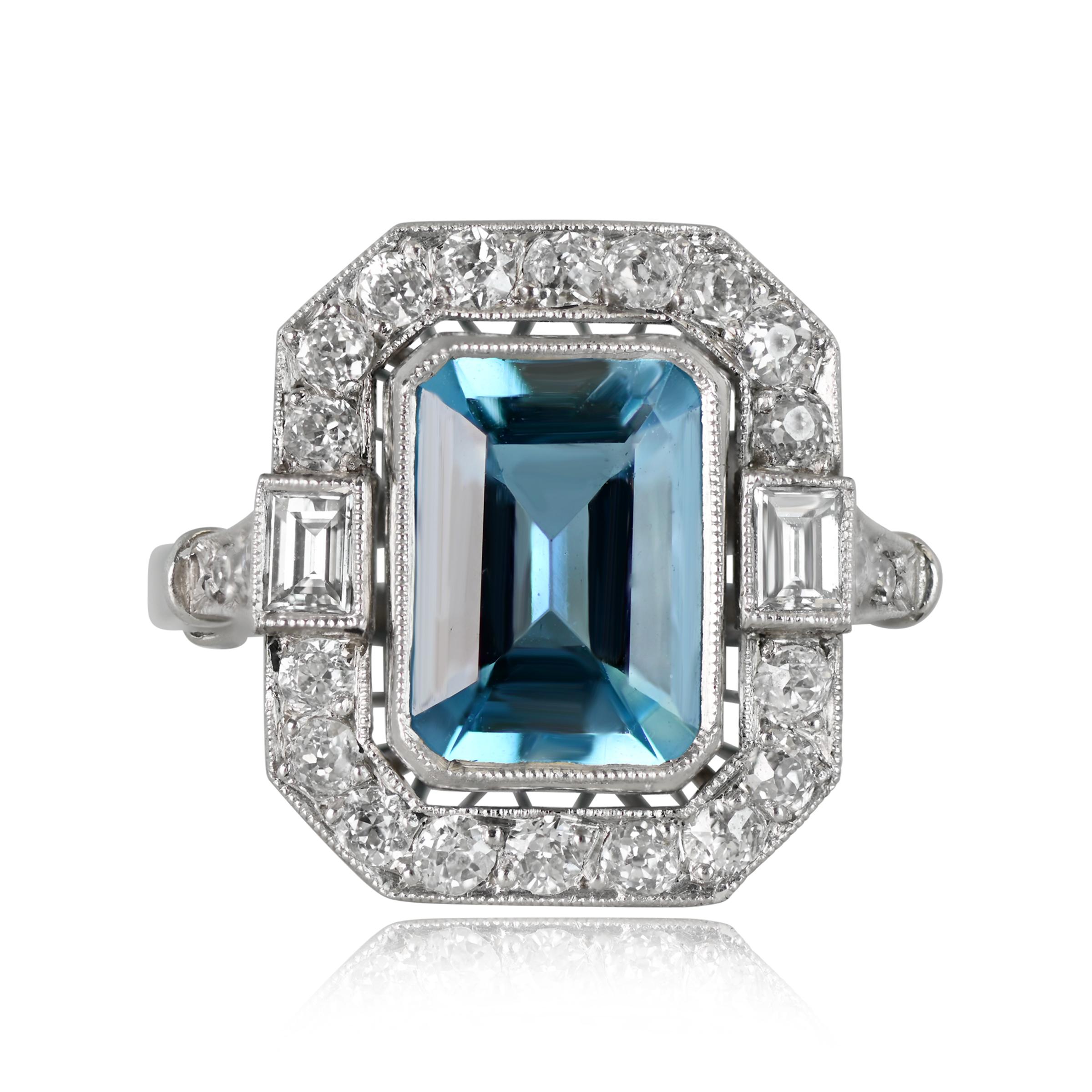 A stunning aquamarine and diamond engagement ring, featuring around 1 carat of diamonds. The center emerald-cut aquamarine is bezel-set, encircled by a diamond halo. Complementing the center stone, two baguette-cut diamonds flank it, and six more