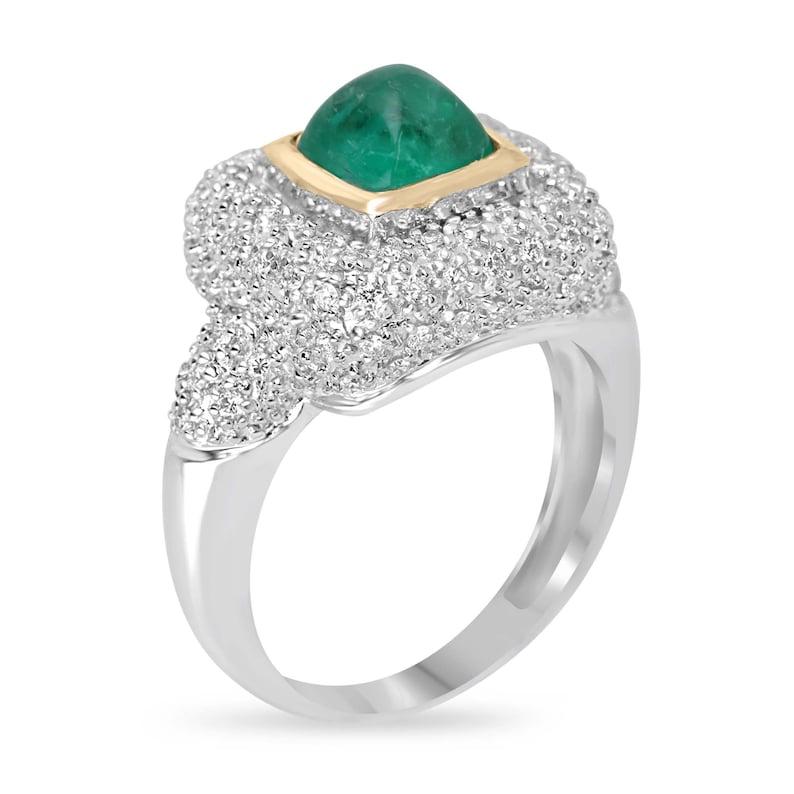 Concediti un fascino senza pari con il nostro squisito anello cocktail con smeraldo e diamante, caratterizzato da un affascinante smeraldo taglio Sugarloaf incastonato al centro, che attira l'attenzione con il suo fascino unico. Brillanti gruppi di