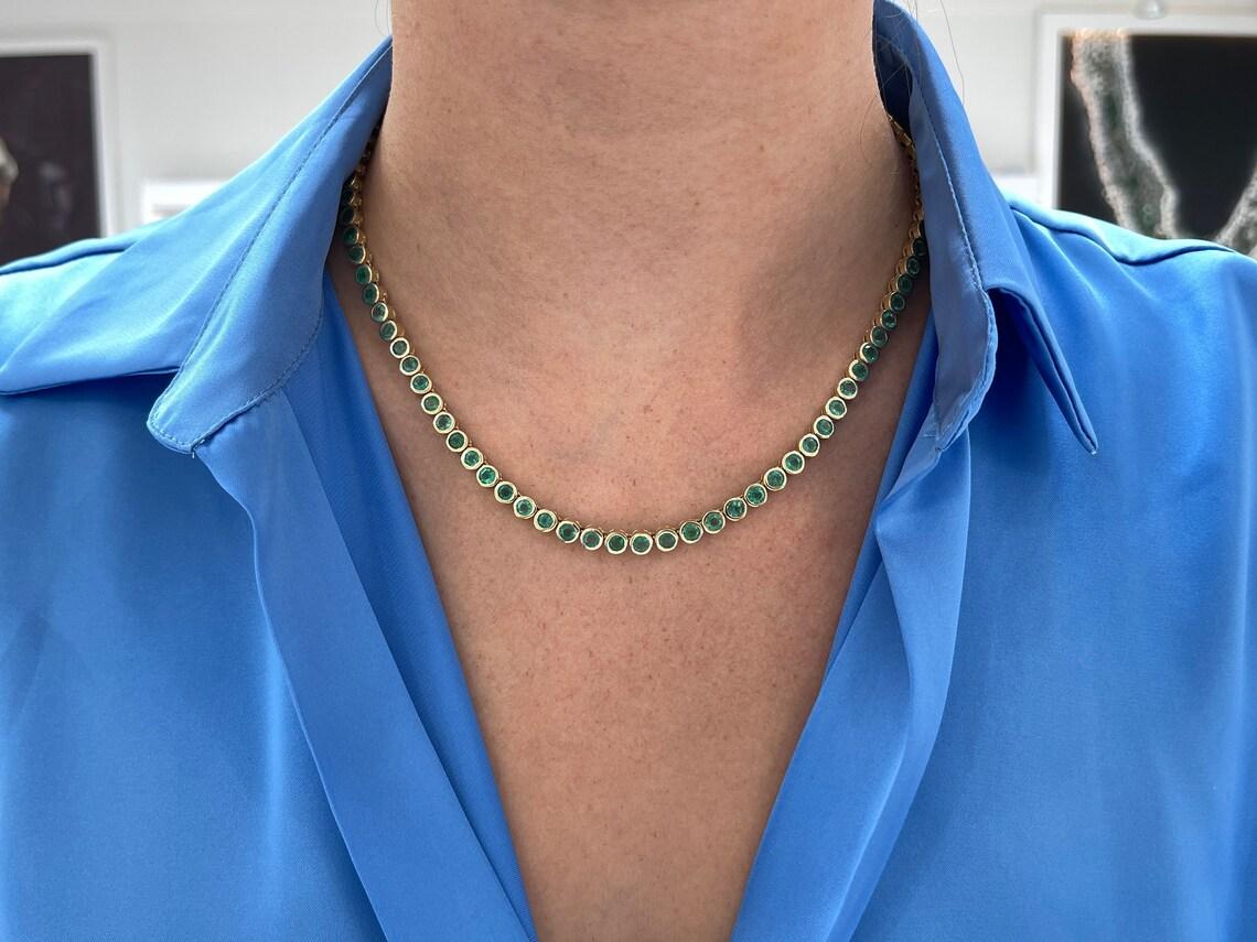 Lasciati sedurre dalla bellezza mozzafiato di questa collana tennis con castone di smeraldi, che vanta oltre 25 carati di smeraldi naturali rari a taglio rotondo provenienti dalle importanti miniere dello Zambia. Gli splendidi smeraldi presentano un