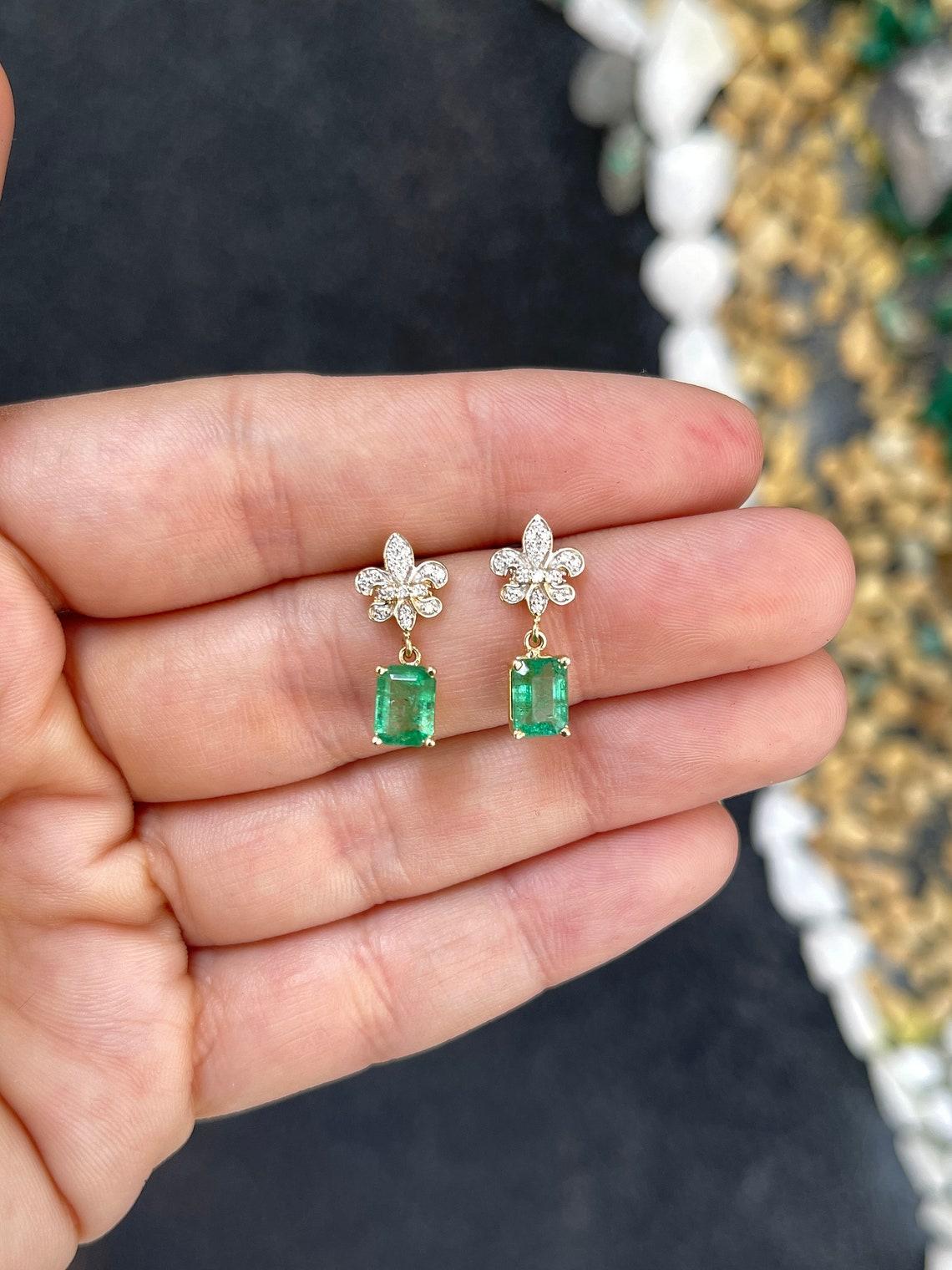 Eleganza senza tempo e bellezza regale, questi orecchini pendenti presentano 2,30 smeraldi taglio smeraldo di peso totale con un accattivante colore verde medio, una sottile tonalità giallastra e una limpidezza semitrasparente. Sospesi da un