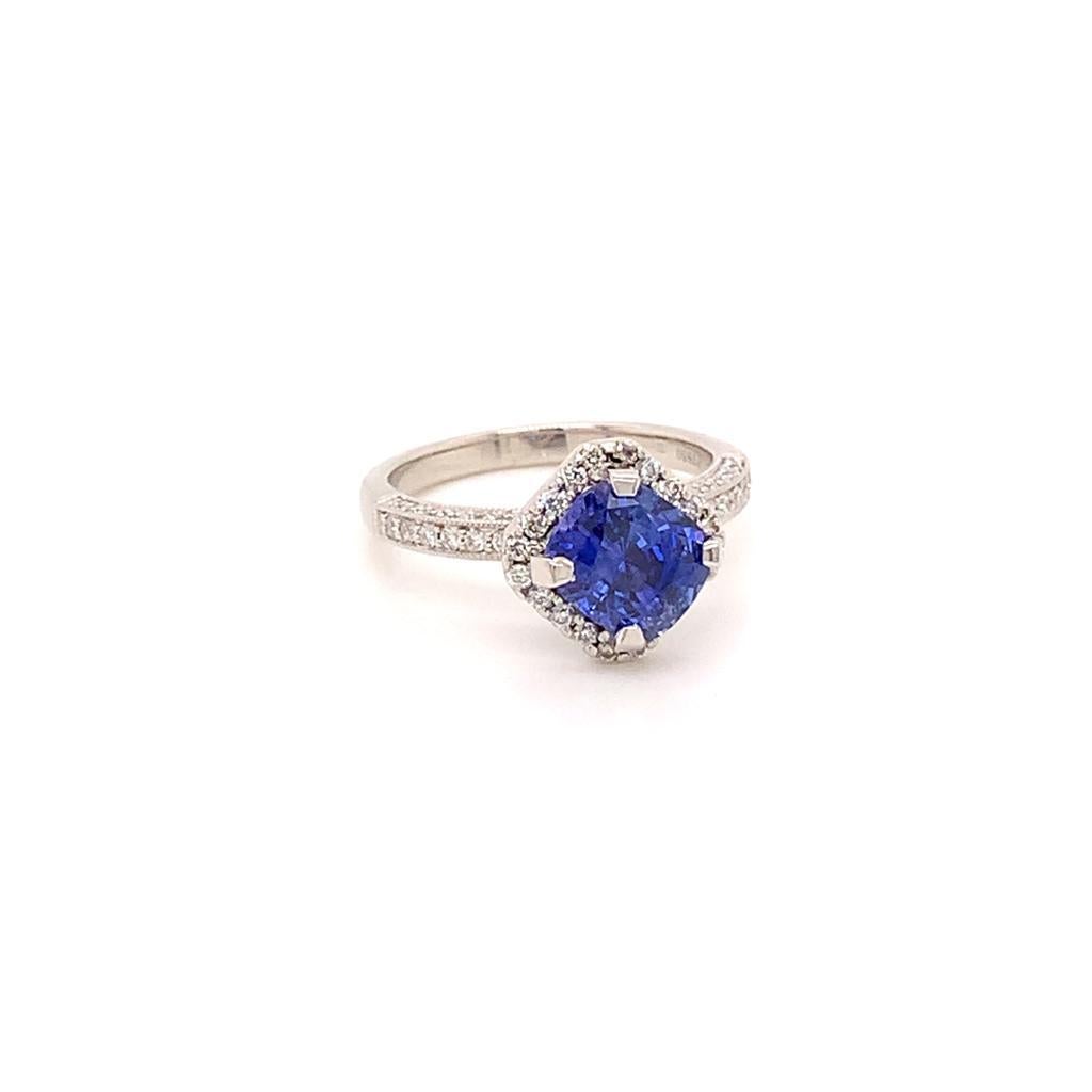 This stunning ring features a vivid Cushion cut Blue Sapphire weighing approximately 2.56 Carats at its centre held by a four-prong setting and surrounded by a halo of scintillating brilliant Diamonds which bring out the intensity of the velvety
