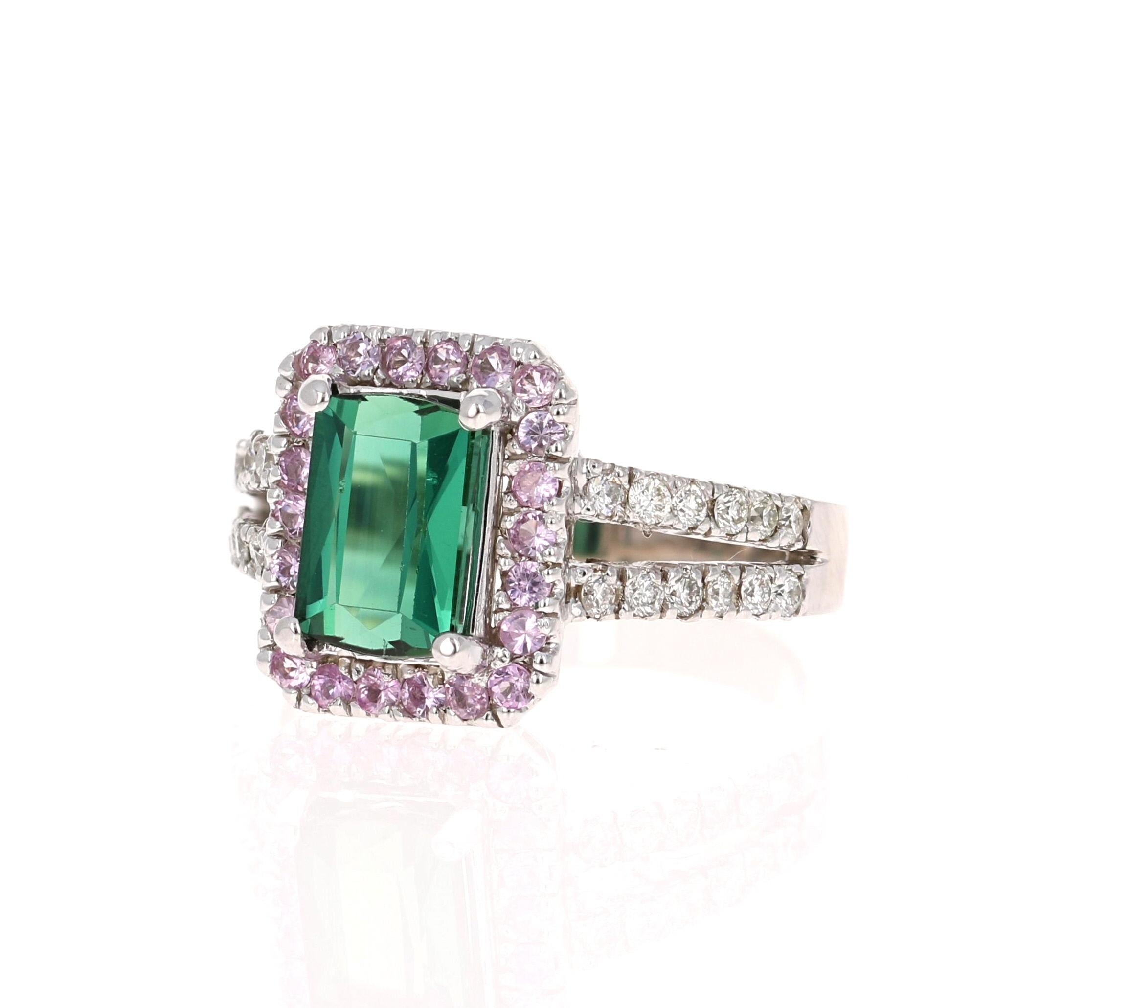 This beautifully designed ring has an Emerald Cut Green Tourmaline that weighs 1.82 Carats and is surrounded by 22 Round Cut Pink Sapphires that weigh 0.38 Carats and 24 Round Cut Diamonds along the shank of the ring that weigh 0.36 Carats (Clarity: