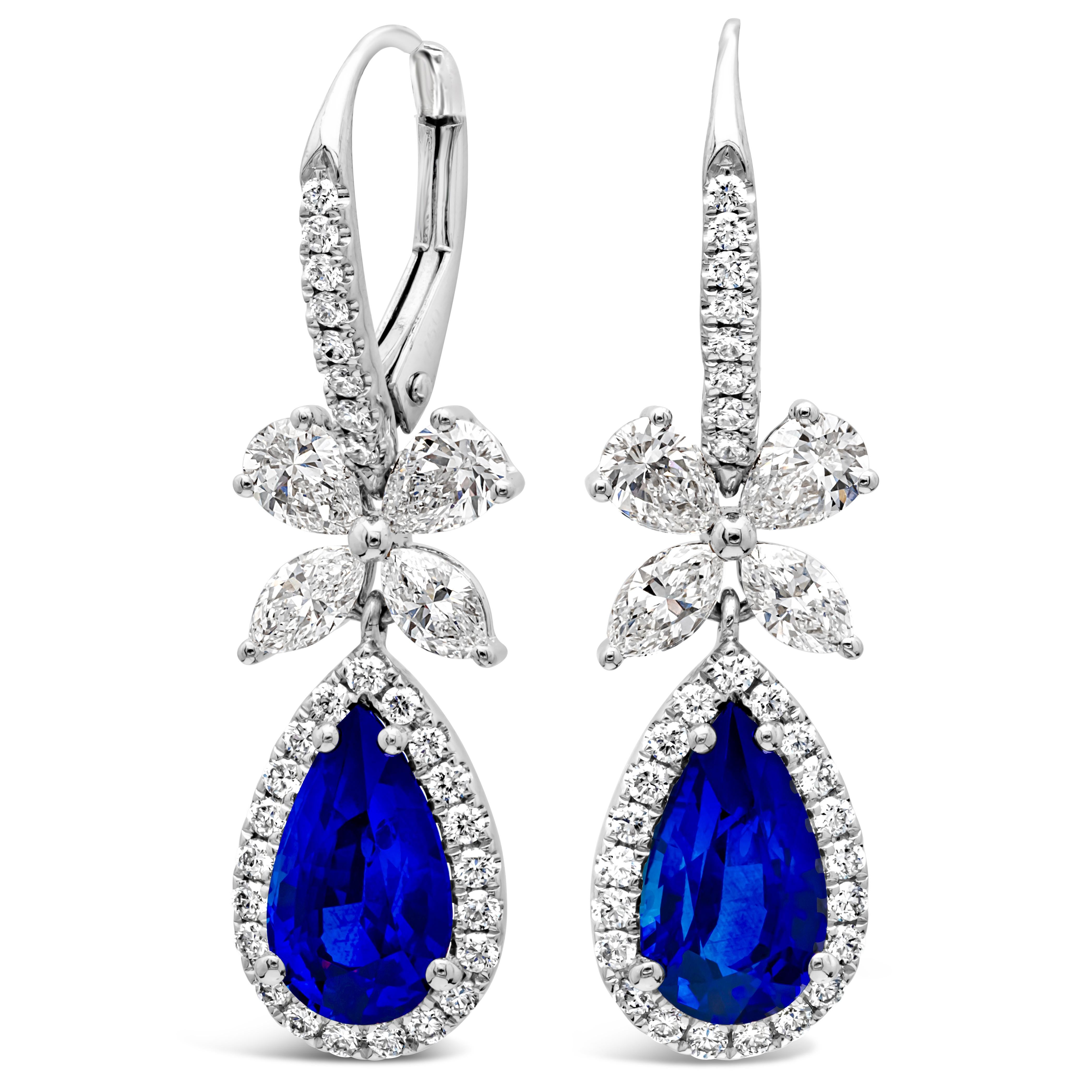 Dieses wunderschöne Paar Ohrhänger besteht aus einem birnenförmigen, farbenprächtigen blauen Saphir mit einem Gesamtgewicht von 2,69 Karat, der von einer Reihe runder Brillanten in einem Halo-Design umgeben ist. Eine bogenförmige Figur aus Diamanten