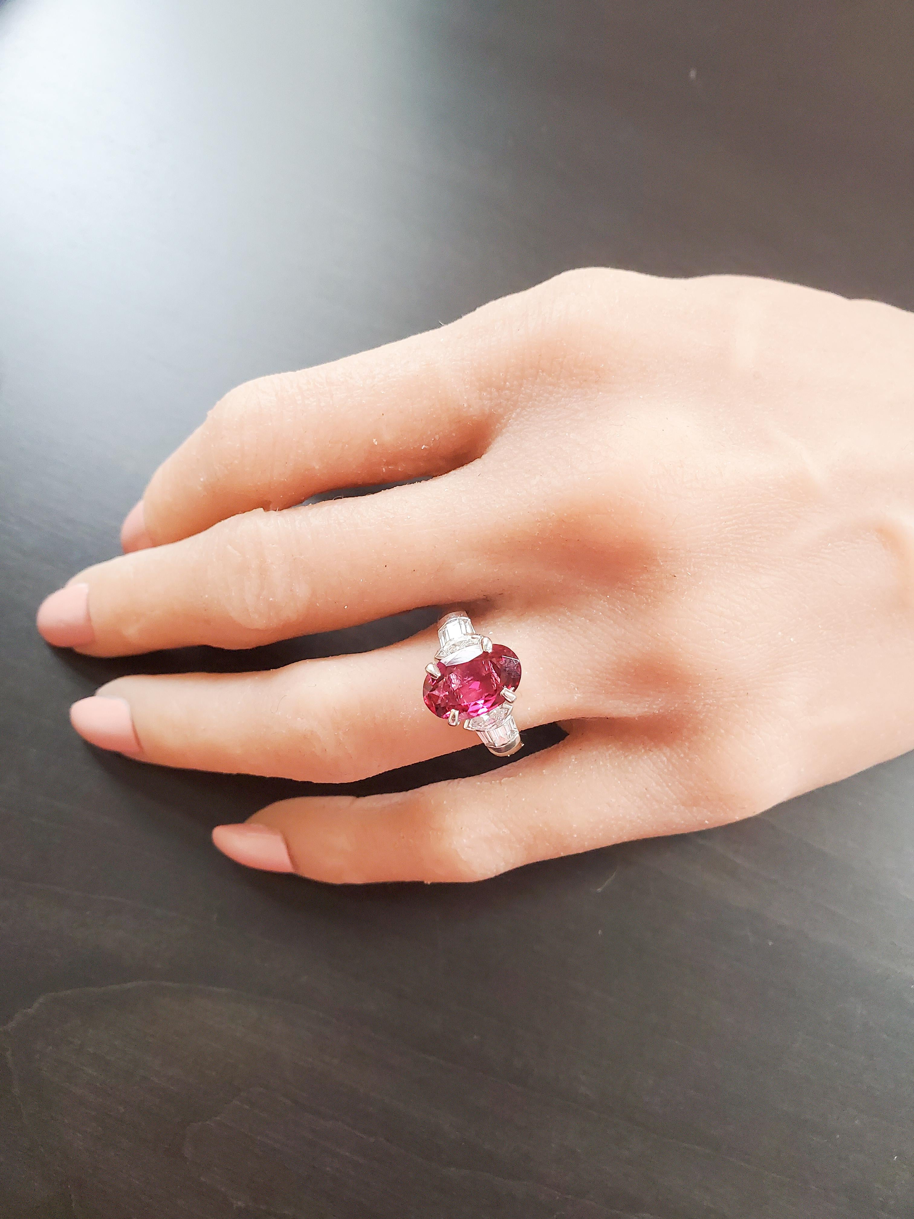 This art deco inspired ring features a natural 2.58 carat oval cut vibrant Brazilian rubellite prong set in the center. The gem source is Brazil; it's size, transparency, and luster are excellent. This alluring rubellite is complemented by 2