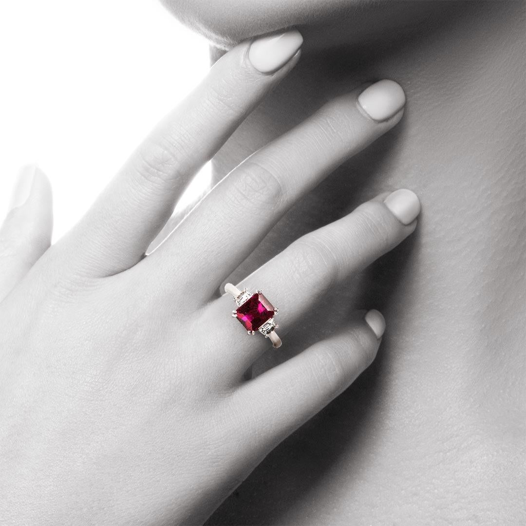 This three -stone ring features a 2.58 carat Emerald Cut Rubellite or red Tourmaline and a pair of Cadi Step cut Diamonds with a total weight of 0.49 carat (Colour F/G, Clarity VS2). A beautiful ring with an Art Deco style and a very special