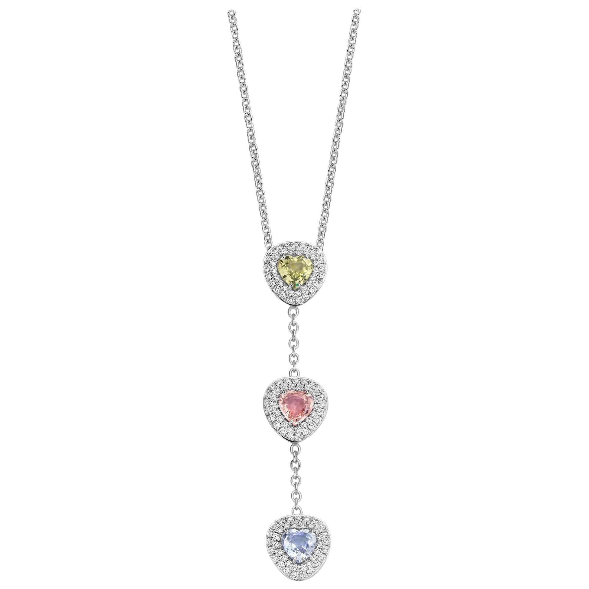 One of a kind three-stone “Didi” necklace in 18K white gold 9,8g set with the finest diamonds in brilliant cut 0,82Ct (VS/F quality) and 3 natural, yellow, pink & purple sapphires in heart cut 2,58Ct. The chain is 42cm long incuding an adjustable