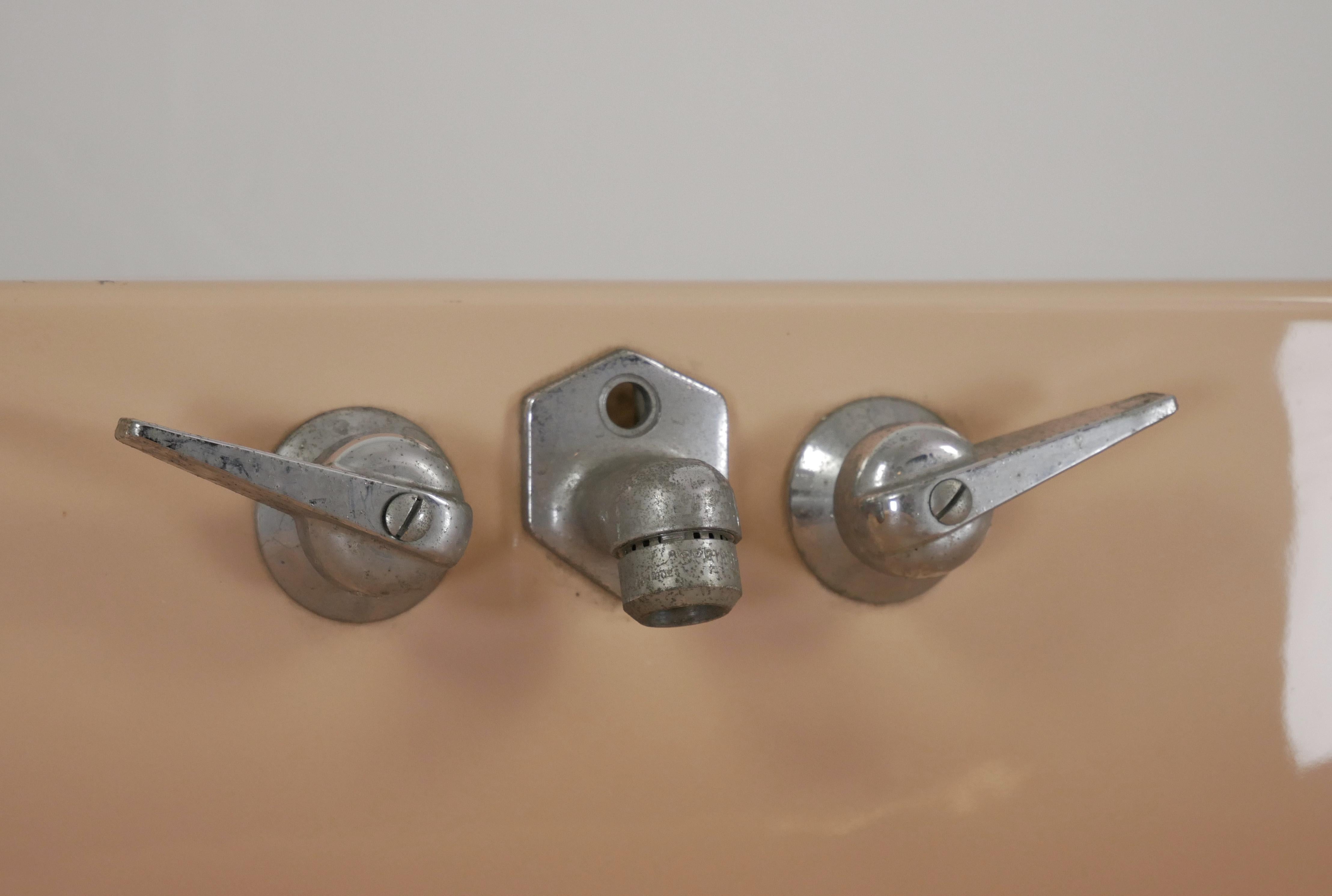 Lavello da parete in ceramica porcellanata color pesca con vasca a forma di rettangolo. La ferramenta originale in nichel è inclusa. In buone condizioni, con graffi superficiali sulla porcellana e usura della finitura sulla ferramenta. Uno