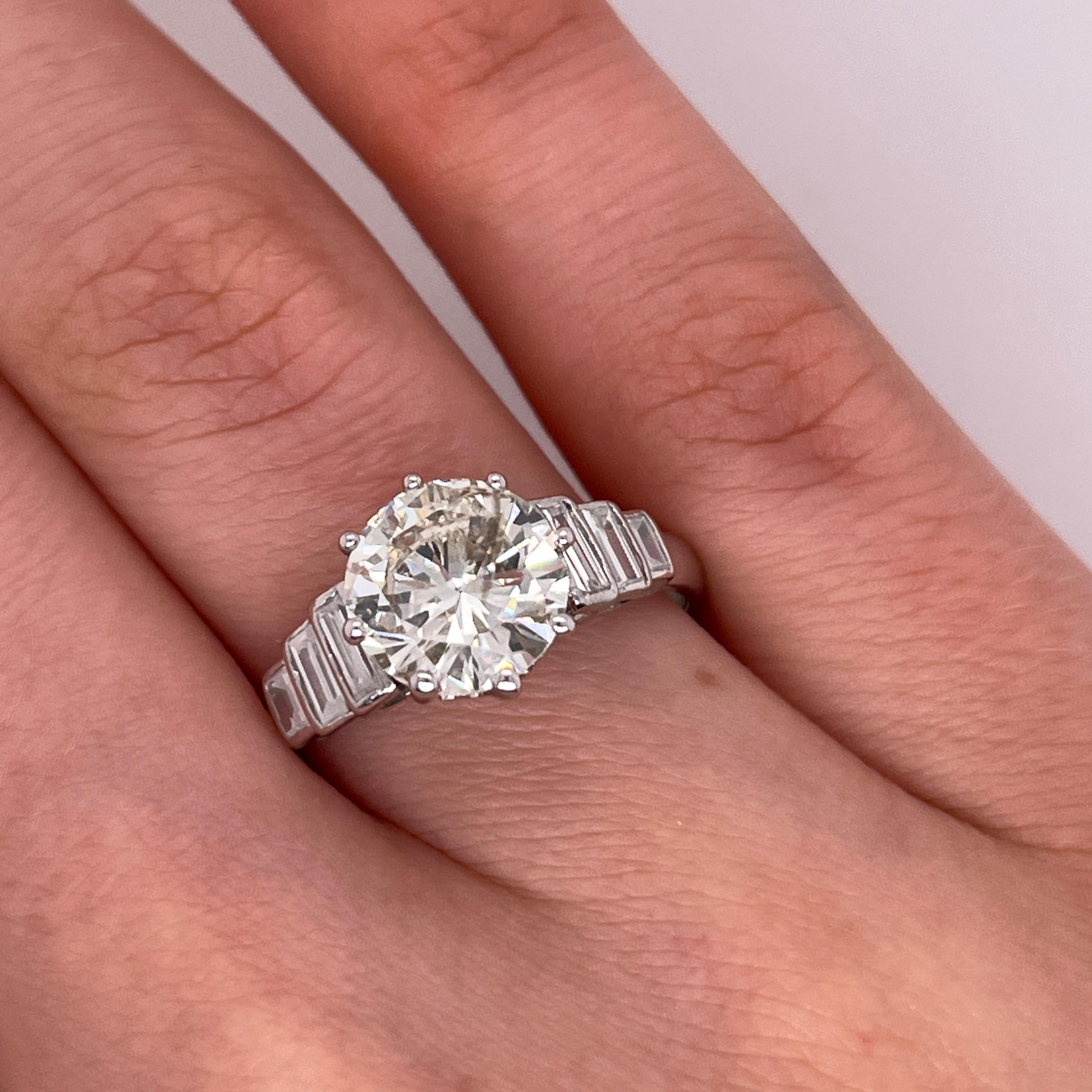 Ein atemberaubender Diamantring mit 2,58 Karat rundem Brillantschliff, gefasst in zeitlosem Platin. 
Der Diamant ist in der Farbe K-L und in der Reinheit SI3 eingestuft, 
Sie bietet ein wunderschönes Funkeln, flankiert von drei Baguette-Diamanten