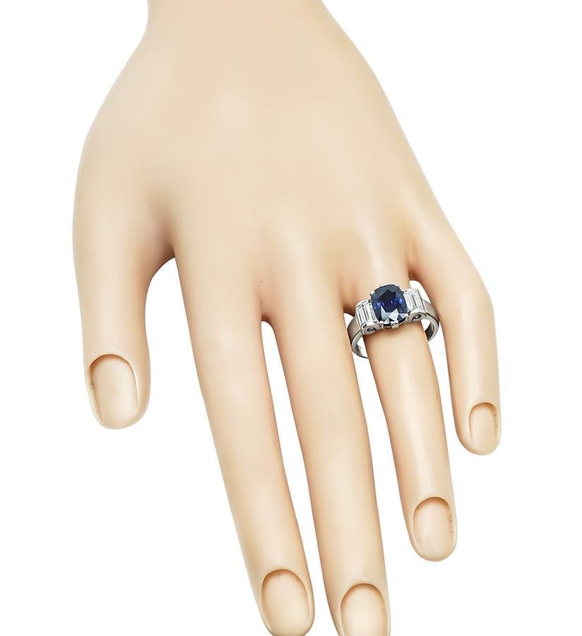 Este es un encantador anillo de compromiso de oro blanco de 14k. El anillo está centrado con un precioso zafiro talla cojín que pesa aproximadamente 2.58 ct. El zafiro está realzado por brillantes diamantes talla baguette de aproximadamente 0.30