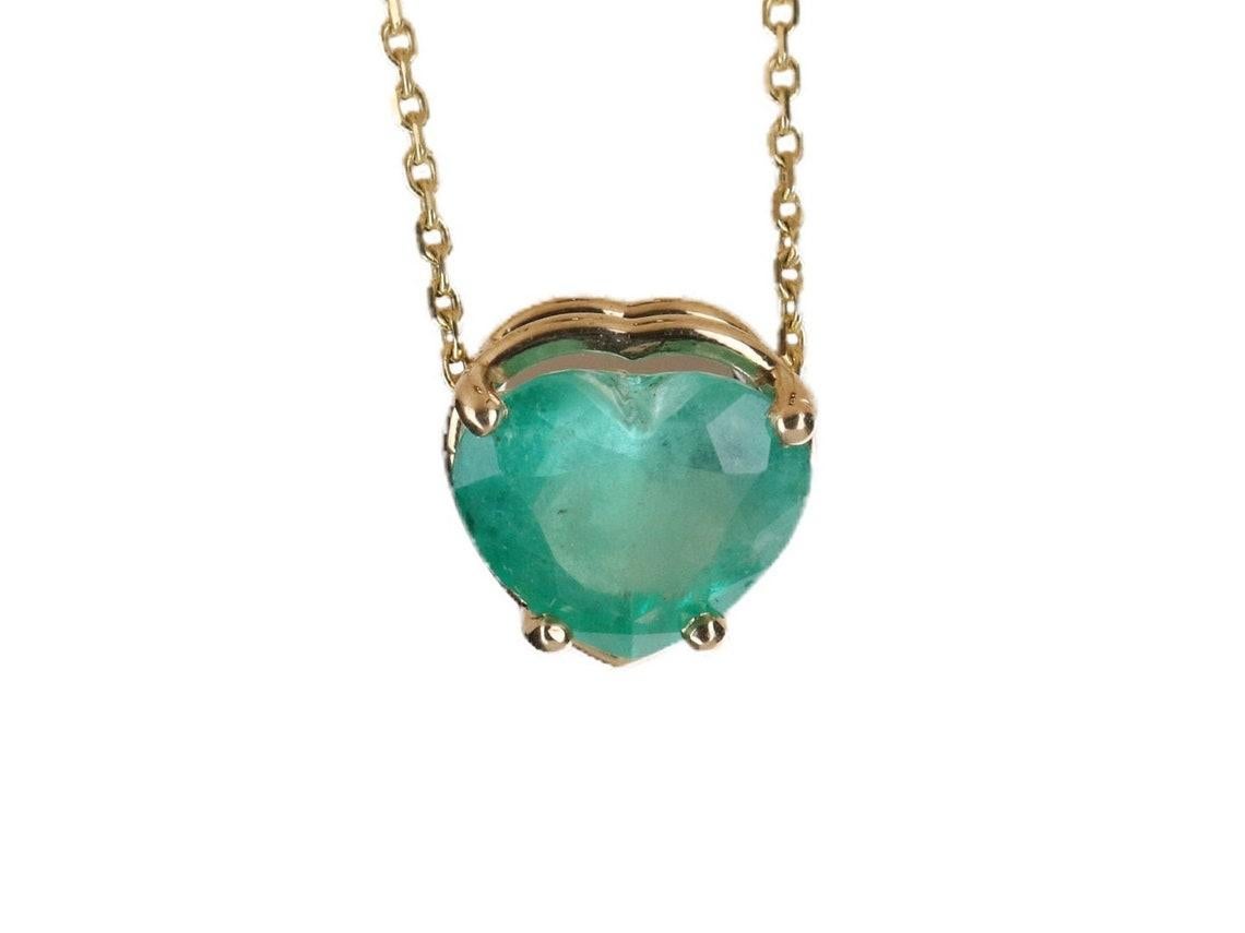 A simple, yet stunning emerald heart slider pendant. This heart-shaped emerald is from the famous mines of Colombia. The emerald displays a beautiful medium green color and very good luster. An 18-inch, 14K yellow gold cable chain is provided with