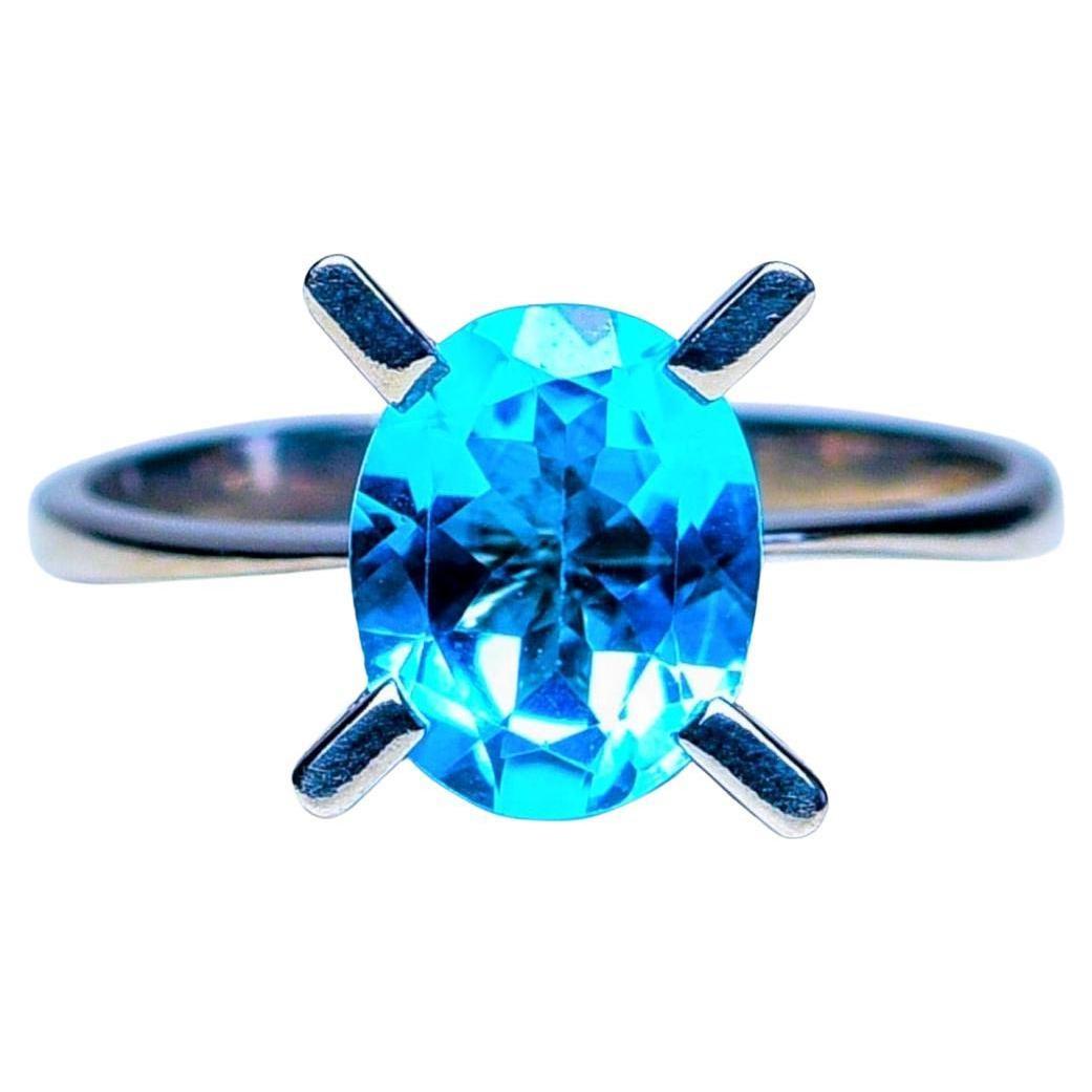 Experience the allure of our 2.5ct Oval Cut Blue Topaz Solitaire Ring. This stunning piece features a single, magnificent 2.5ct Oval Cut Blue Topaz as its centerpiece. The blue topaz, known for its calming blue hues and clarity, is beautifully