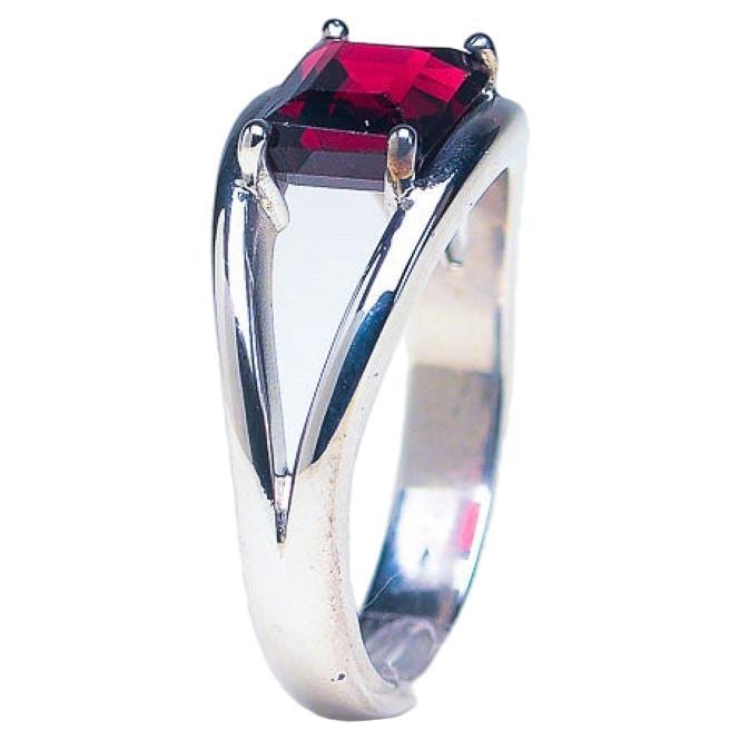 Unser 2,5-karätiger Ring mit rotem Granat im Kissenschliff aus Platin-Silber ist ein atemberaubendes Stück, das Eleganz und Raffinesse ausstrahlt. In der Mitte dieses Rings befindet sich ein faszinierender roter Granat von 2,5 Karat im