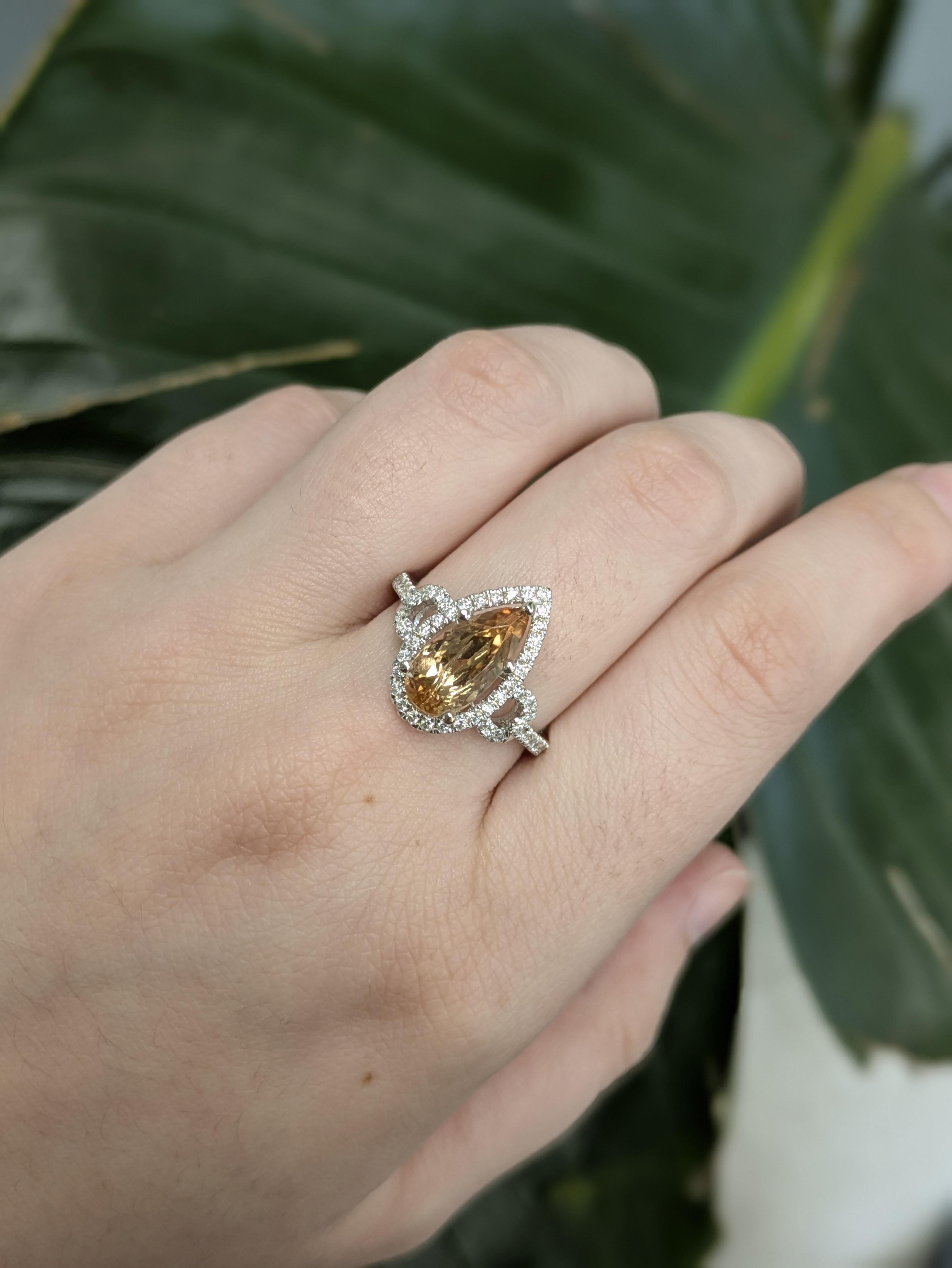 This graceful ring features a 2.53ct pear-shaped Imperial Topaz from Brazil, measuring 12.3x6mm and heat-treated to enhance its warm, golden hue. Set in 14k gold (3.13g), the center stone is beautifully framed by 55 sparkling diamonds totaling
