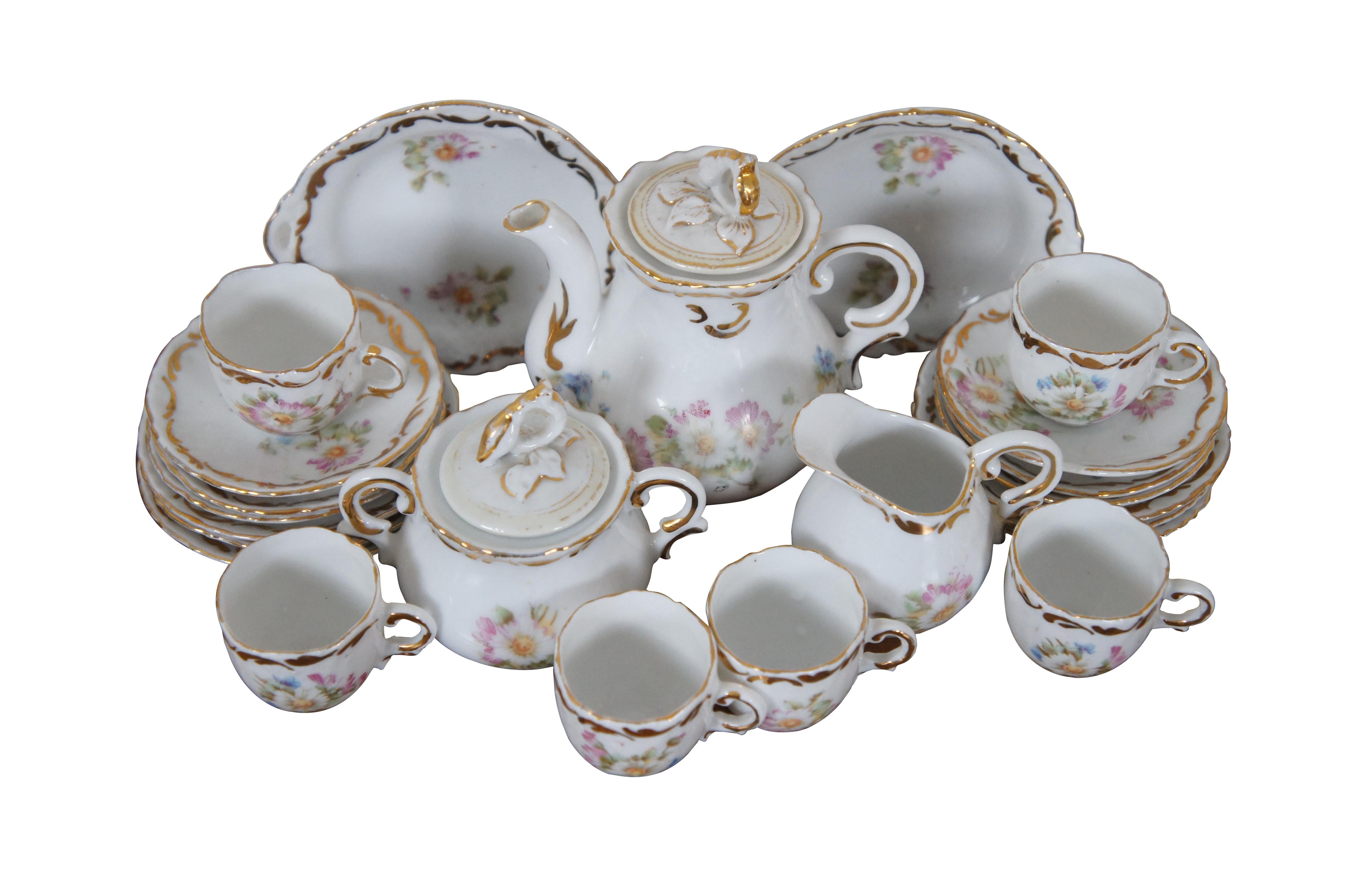 Early 20th century child’s miniature / dollhouse porcelain tea set featuring gently scalloped edges with gilded foliate accents and a printed pattern of pink and white daisies and blue forget-me-nots. Set includes 2 serving plates, 6 dessert plates,