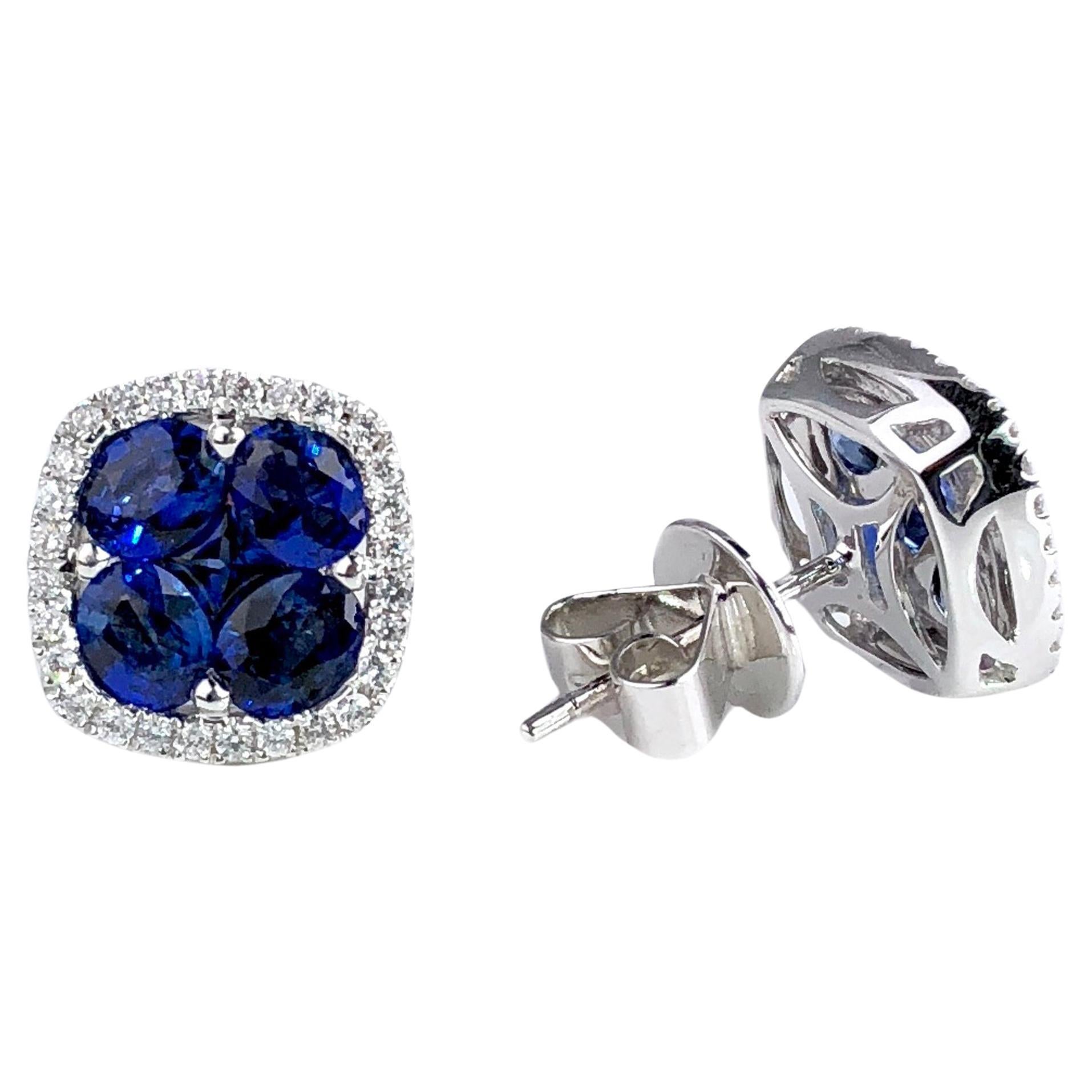 Discover these stud earrings, showcasing a captivating cluster of five exquisite blue sapphires per earring, totaling 2.6 carats, elegantly encircled by a glistening halo of round natural diamonds with a combined weight of 0.21 carats. Set in