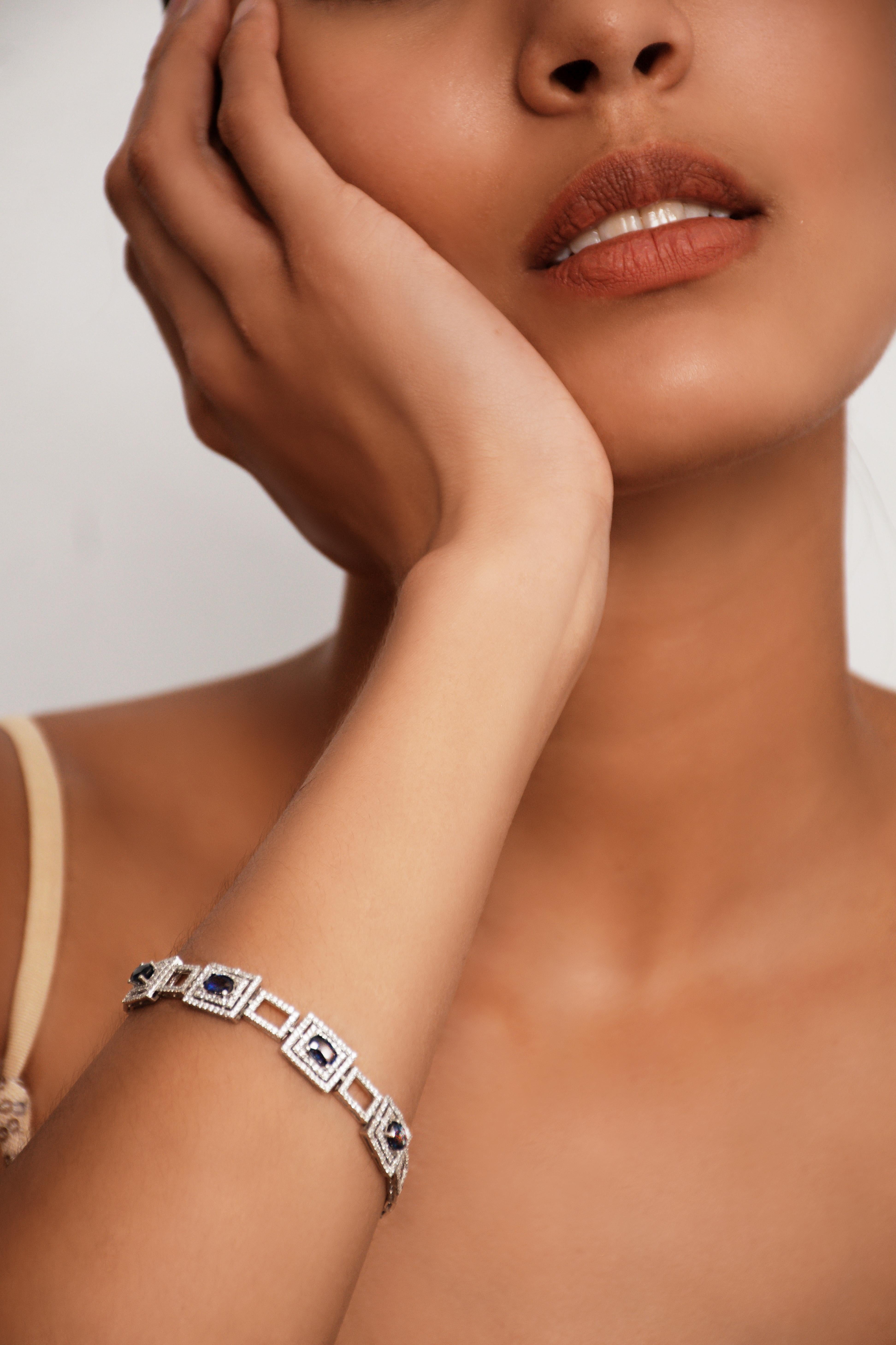 This is a 2.6 CTW natural Sapphire & Zircon Platinum Sterling Silver Chain Bracelet adorned with natural origin blue sapphires. This stunning piece features four oval-shaped sapphires, each weighing 0.5ct and measuring an average of 6x4mm. The deep