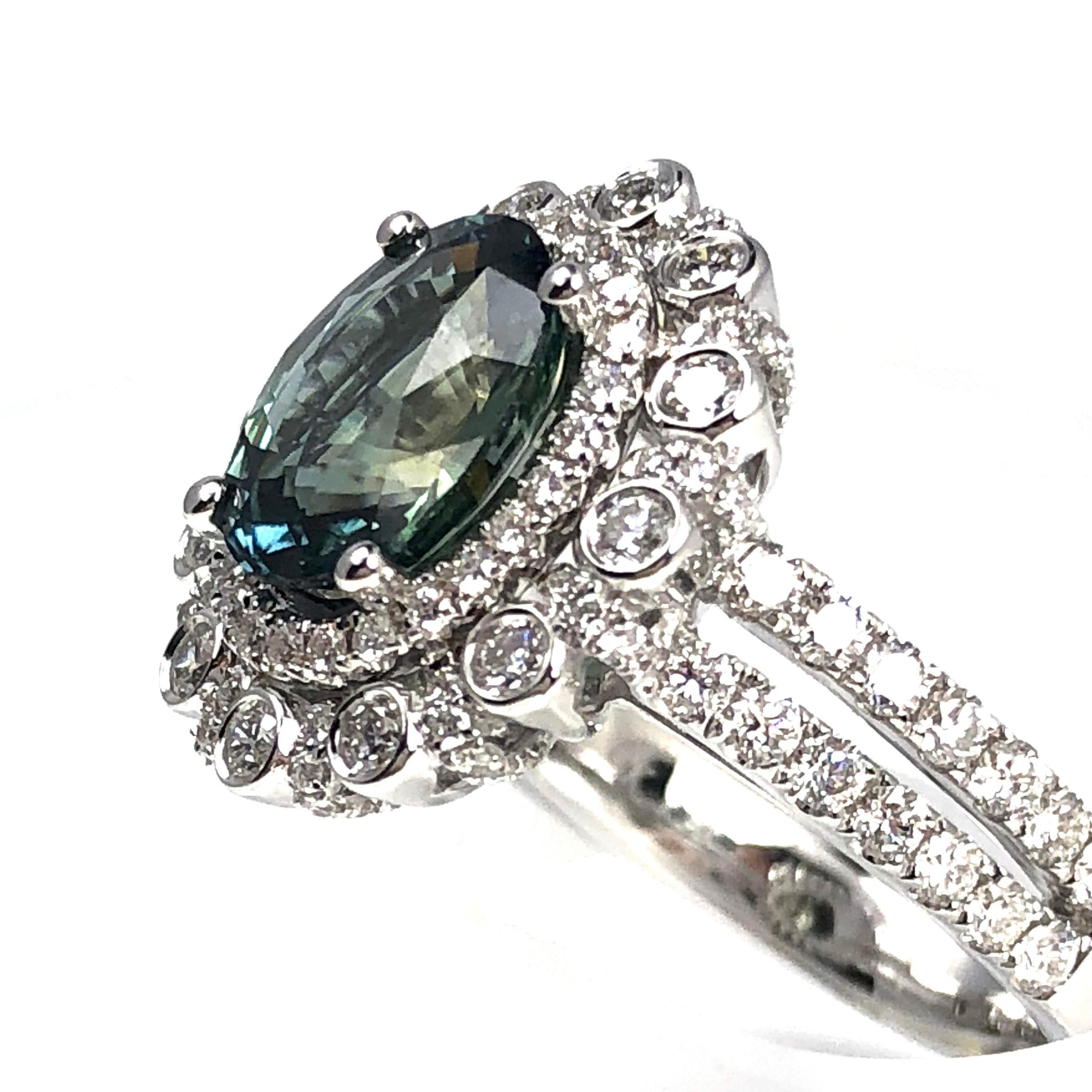 This ring features a 2.60 carat oval cut Green Sapphire center, surrounded by round white diamonds in a double halo. Additional diamonds trail down the split shank, bringing the total diamond weight to 1.03 carats.

Center: 2.60 carats Green
