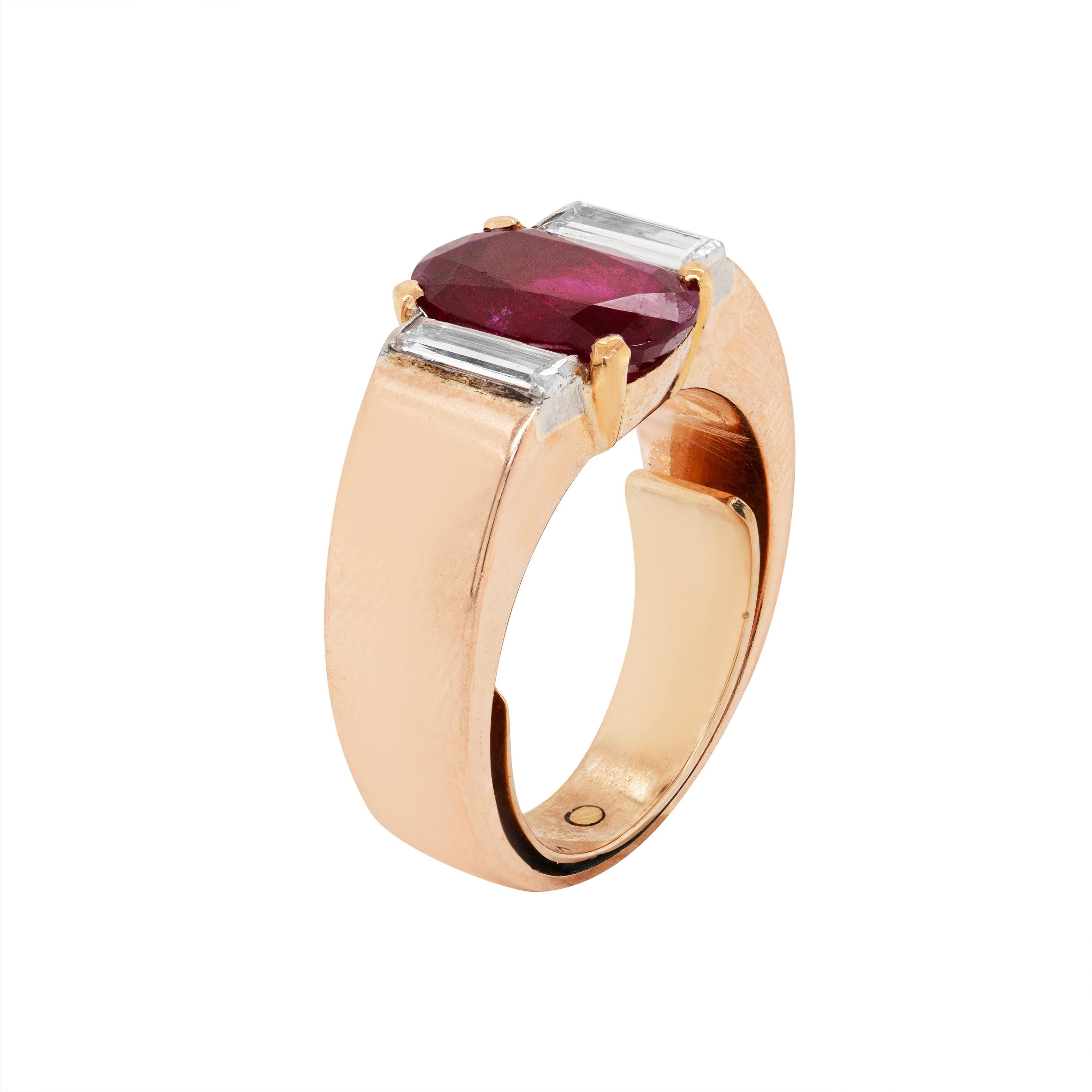 This vintage ring features a 2.60 carat vibrant cherry red oval ruby in a four claw open back setting. The beautiful stone is accompanied by two fine quality baguette cut diamonds weighing approximately 0.25 carat each in a solid 18 carat yellow