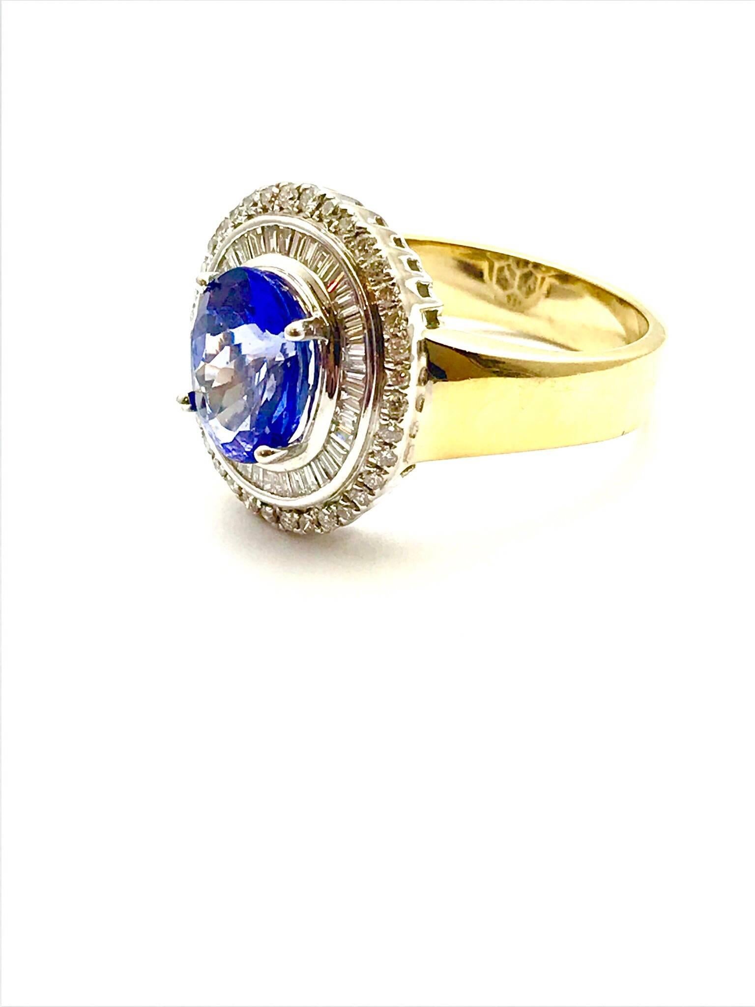 A 2.60 carat tanzanite and diamond 18 karat white and yellow gold fashion ring.  The oval tanzanite is set with four prongs, surrounded by a single row of baguette diamonds, which is framed in by a single row of round brilliant diamonds, all set in