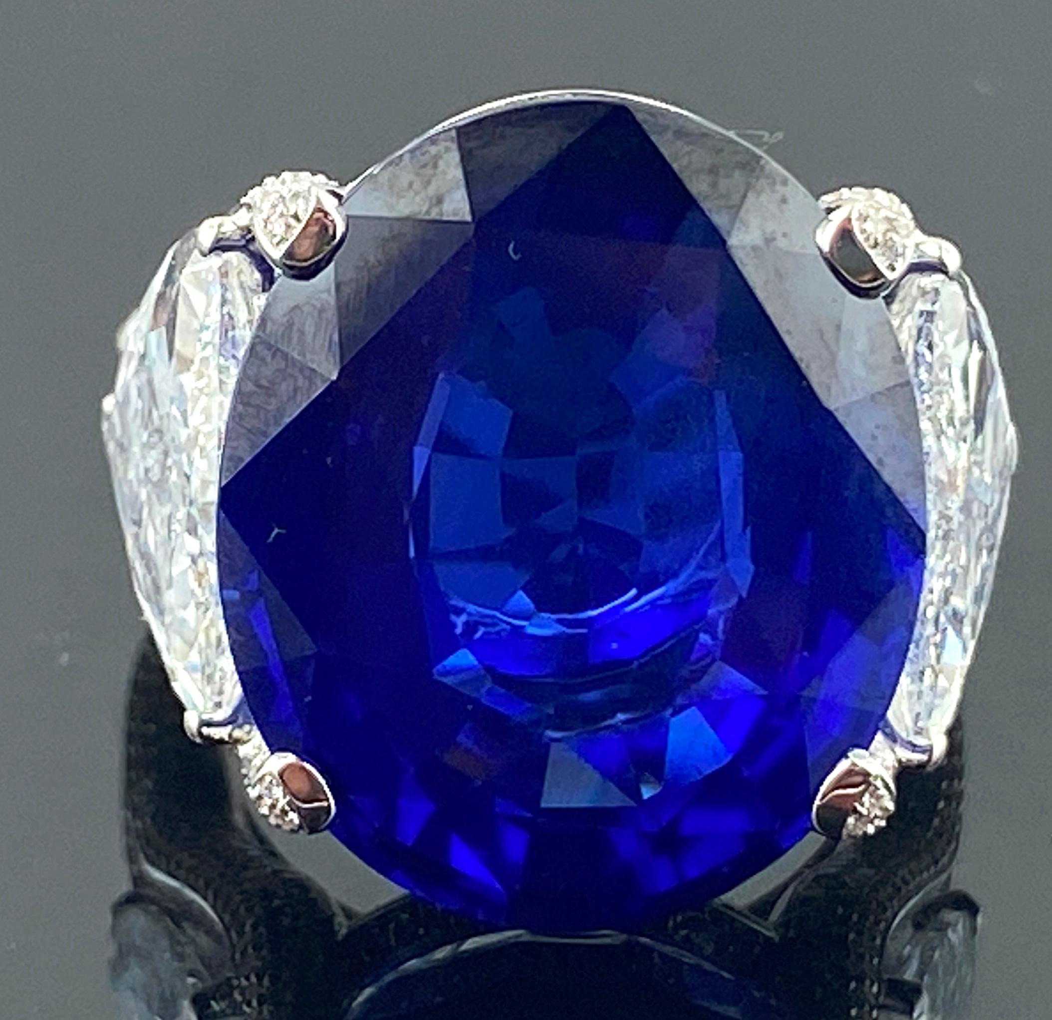 Set in 18 karat white gold is a 26.08 Oval shaped Blue Sapphire with 2 Trillion cut diamonds on the side - 2.03 carats and 2.06 carats, both GIA certified.  Also in mounting are 472 round brilliant cut diamonds with a total weight of 1.09 carats. 