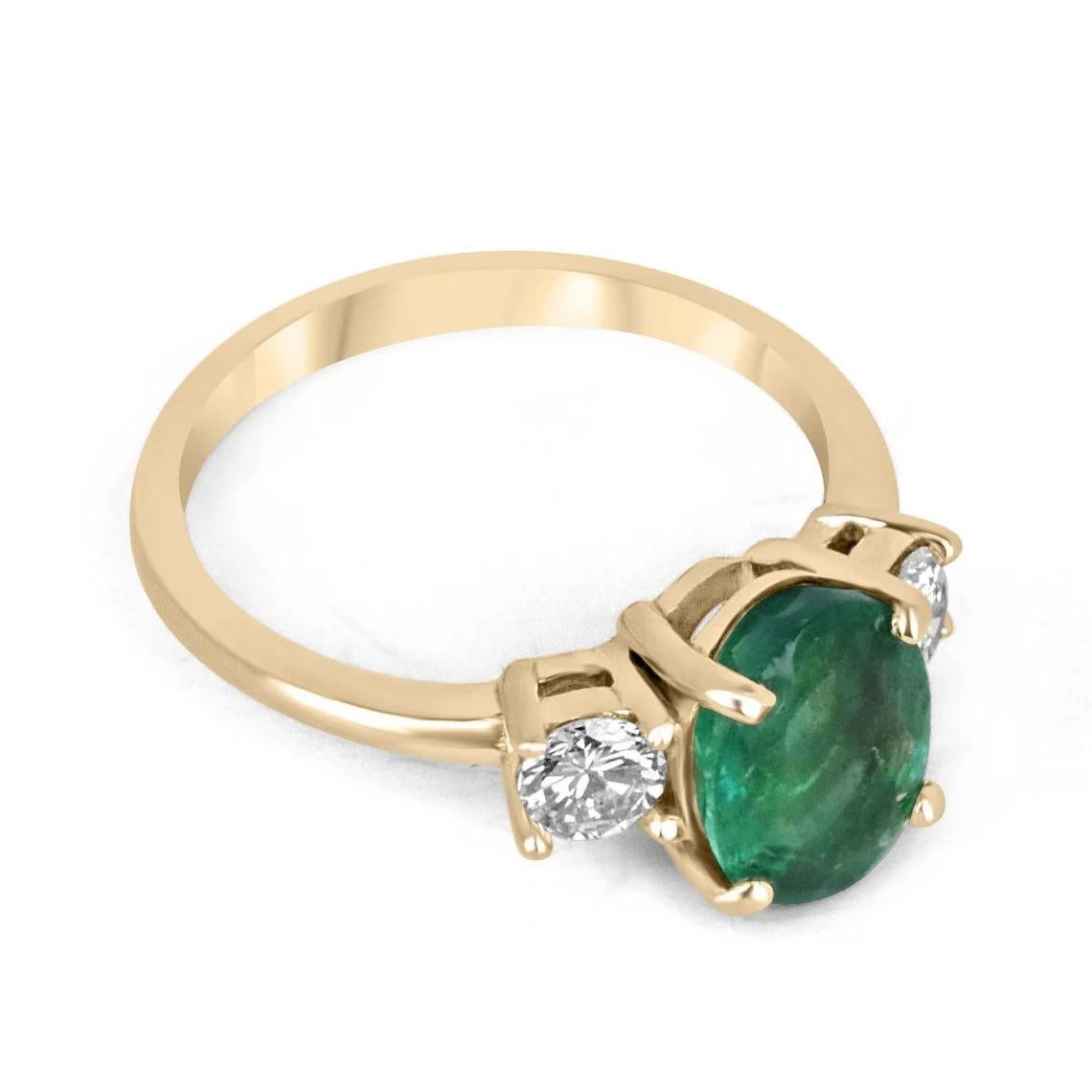 This emerald three-stone ring features a striking 2.10-carat oval-cut emerald as the centerpiece, boasting a captivating dark and lush green color. The emerald is beautifully complemented by brilliant round-cut diamonds, which delicately accentuate
