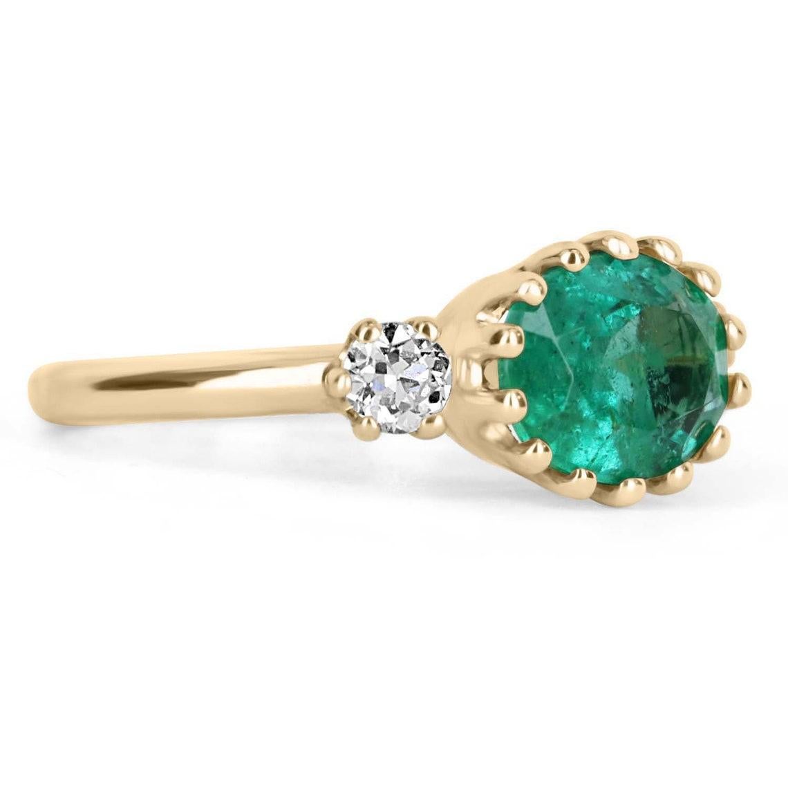 Featured here is a redefined emerald and diamond three-stone ring. This eccentric design showcases a natural 2.20-carat oval emerald set in a 14-prong setting. Accented are two brilliant round diamonds also set in a 5-prong setting on both sides.