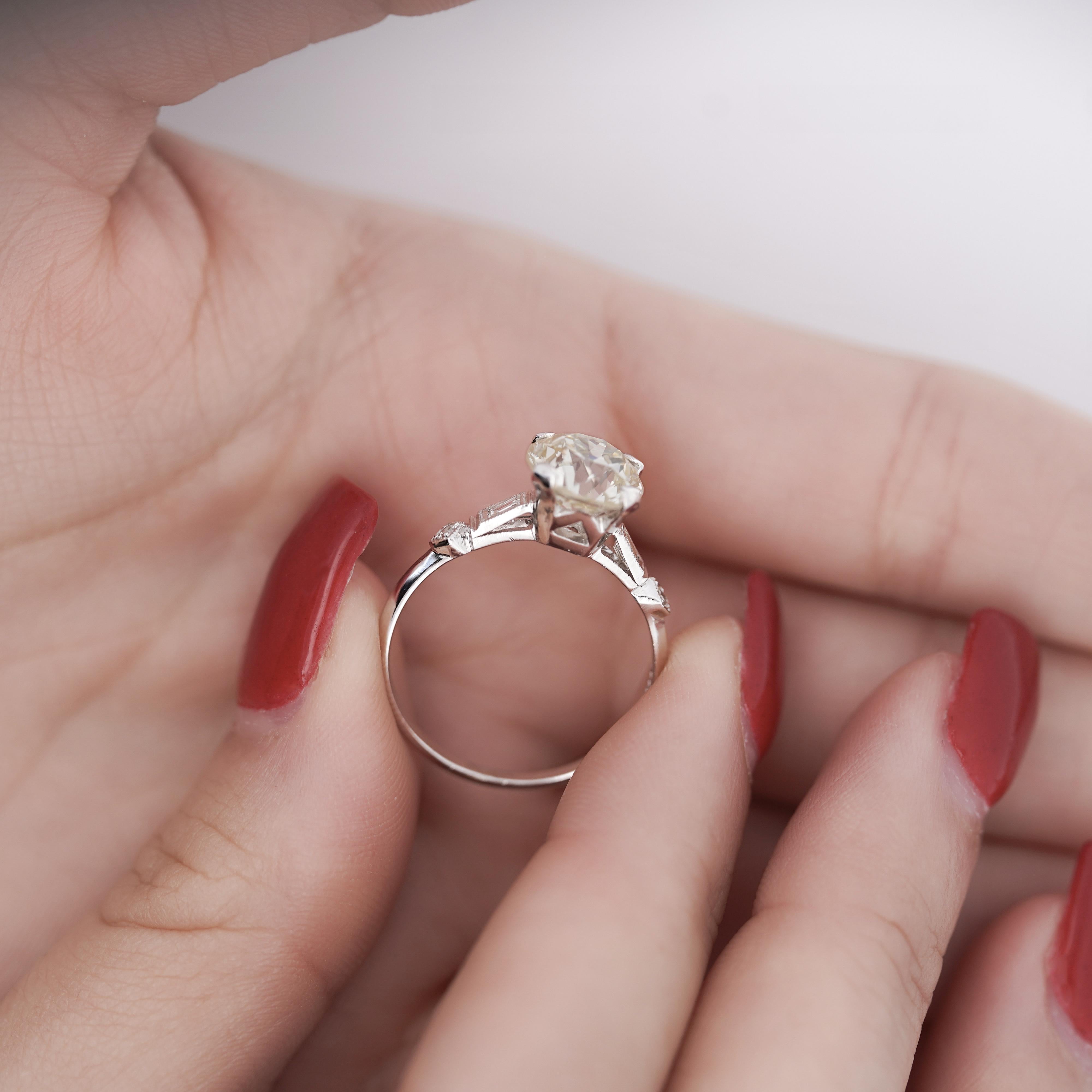 EGL Certified Natural 2.61 Carat European Cut M-N color, VS1 clarity Diamond Vintage Art Deco Engagement Ring. Set in a vintage platinum setting with stunning filigree and milgrain finishes on the shank. The center stone is flanked by 4 baguette cut