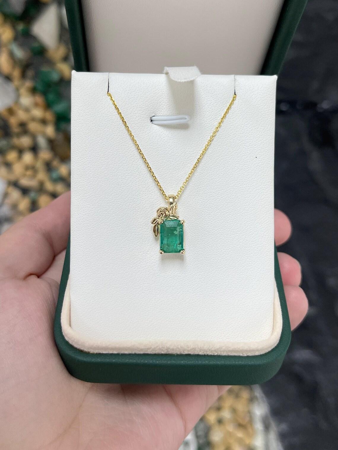 Questo elegante ciondolo floreale solitario presenta uno smeraldo dello Zambia dal taglio a smeraldo, con una tonalità verde brillante e una chiarezza semitrasparente. La gemma è tenuta saldamente in una montatura a quattro punte, ornata da delicati