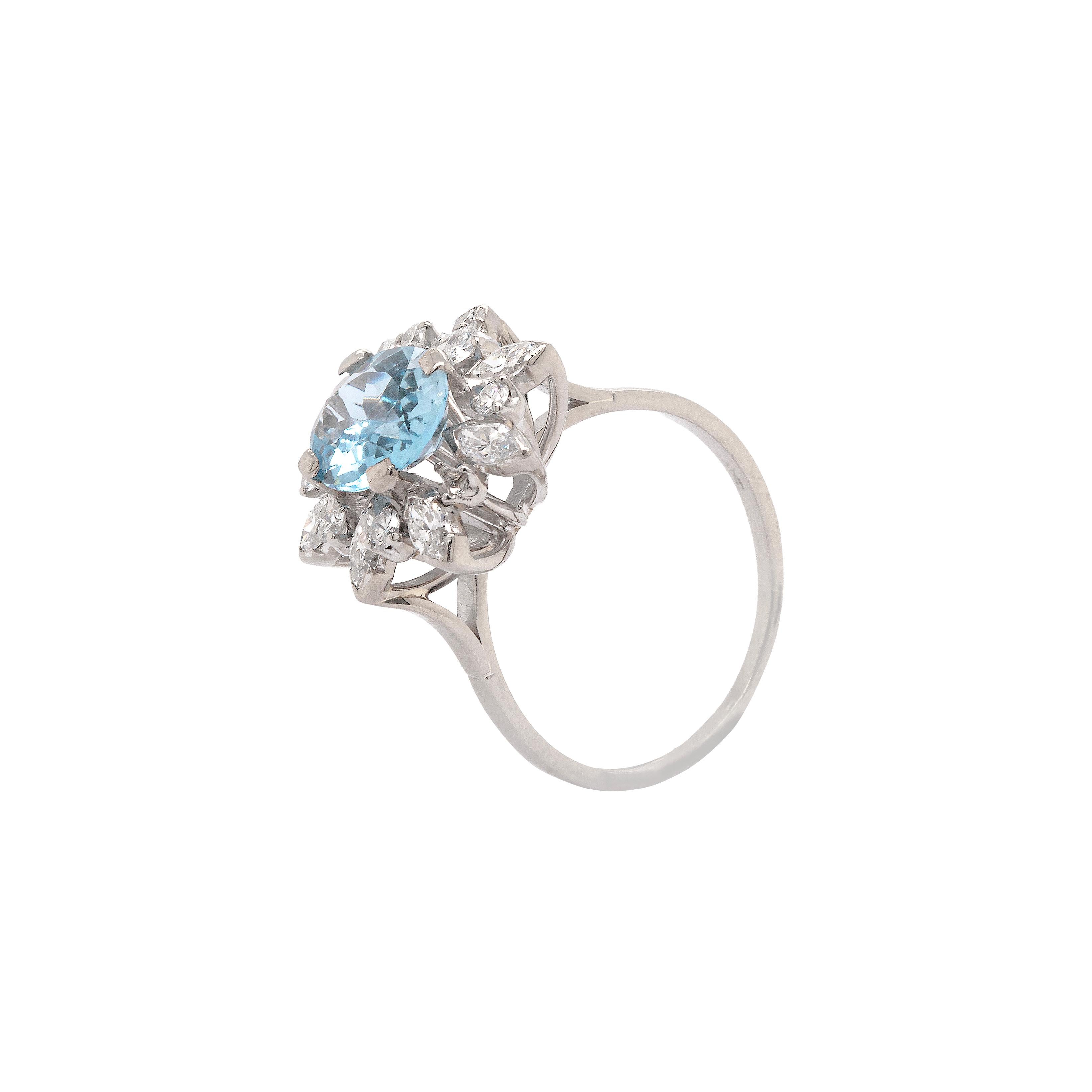 This vintage cluster engagement ring features a vibrant oval aquamarine in the centre weighing 2.61 carats mounted in a four claw, open back setting. The gemstone is perfectly surrounded by alternating marquise and brilliant cut diamonds giving a