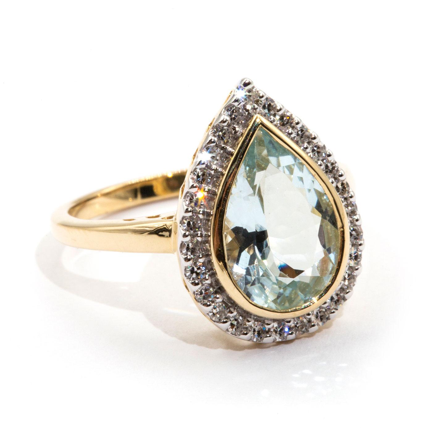 Made in 9 carat yellow gold is this breathtaking vintage inspired Lacey Ring that boasts a romantic pear cut 2.62 carat bright light blue Aquamarine encompassed by a gorgeous halo border of carefully claw set round diamonds. We have name this