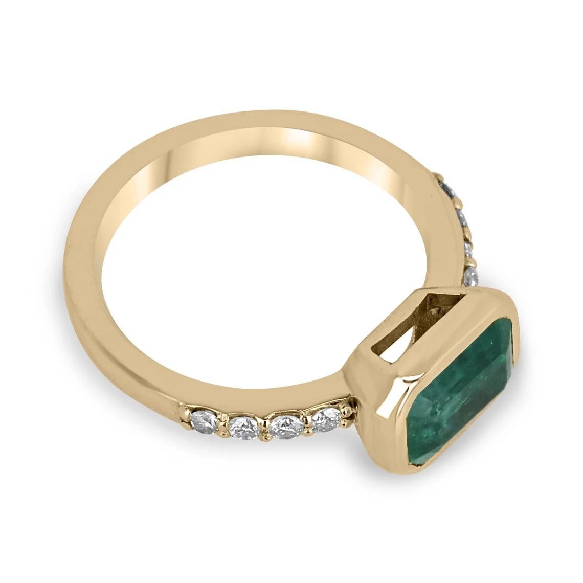 Displayed is a contemporary emerald and diamond engagement ring/right-hand ring in 14K yellow gold. This gorgeous ring carries a full 2.37-carat emerald cut emerald in a bezel setting which adds extra protection for the stone. Fully faceted, this