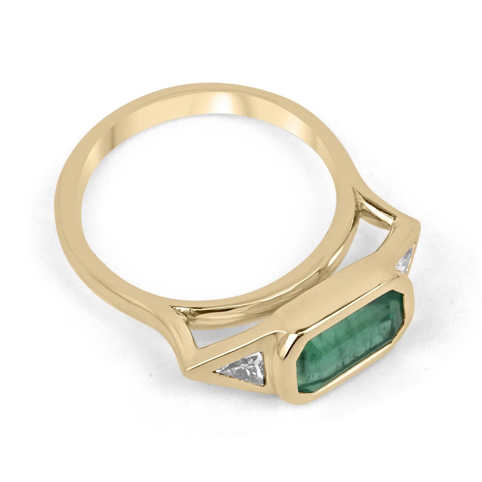 Featured here is a gorgeous emerald and diamond three-stone ring. The center stone is a stunning 2.32-carat, natural emerald-emerald cut. This gemstone displays medium green color and very good eye clarity. Accented on the sides are two trillion-cut