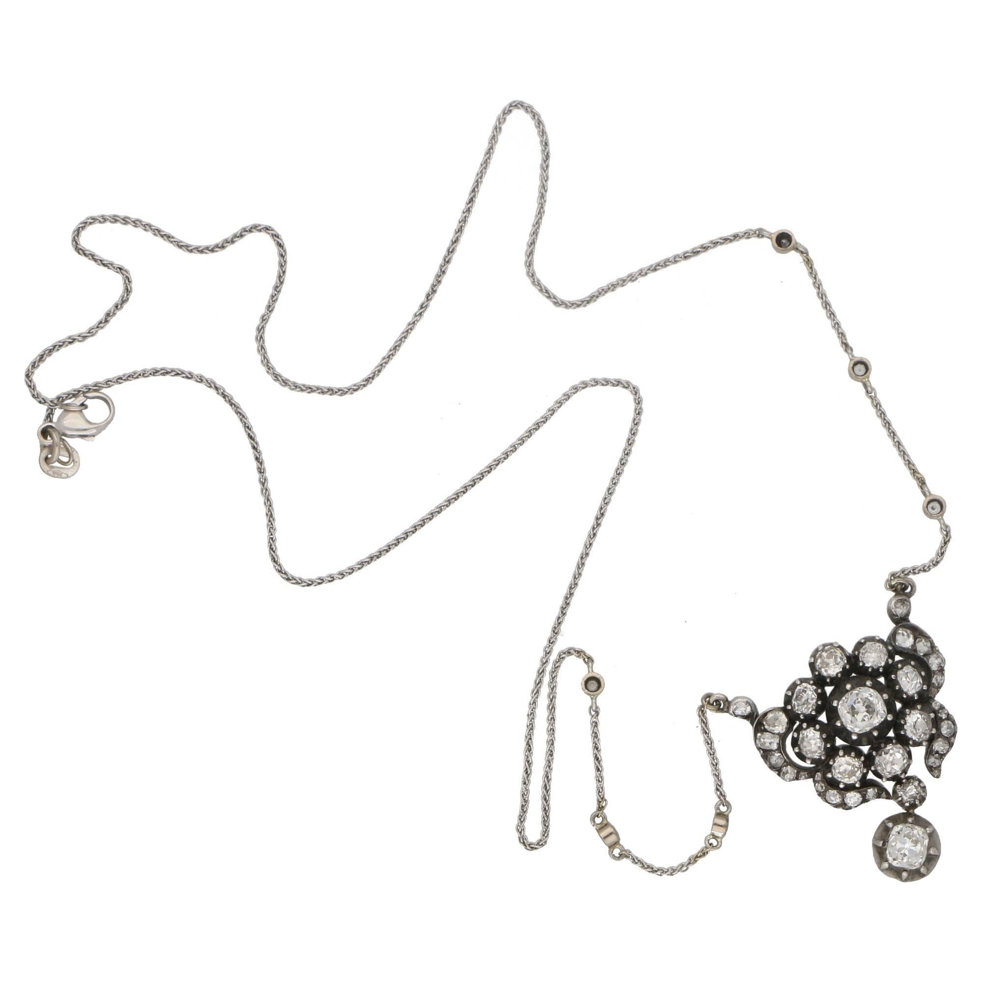 An elegant diamond floral necklace set in the distinctive Victorian setting of silver-on-gold. 

The necklace centrally features a diamond cluster design comprising of 9 old mine cut diamonds. The cluster is then surrounded by a stylised diamond
