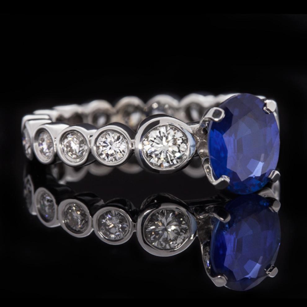 A fantastic 2 carat diamond ring with a stunning 2.64 carat natural sapphire. It is a unique piece composed of bezel-set diamonds that revolve around the ring in a complete eternity. The center stone is a natural royal blue sapphire with a gorgeous