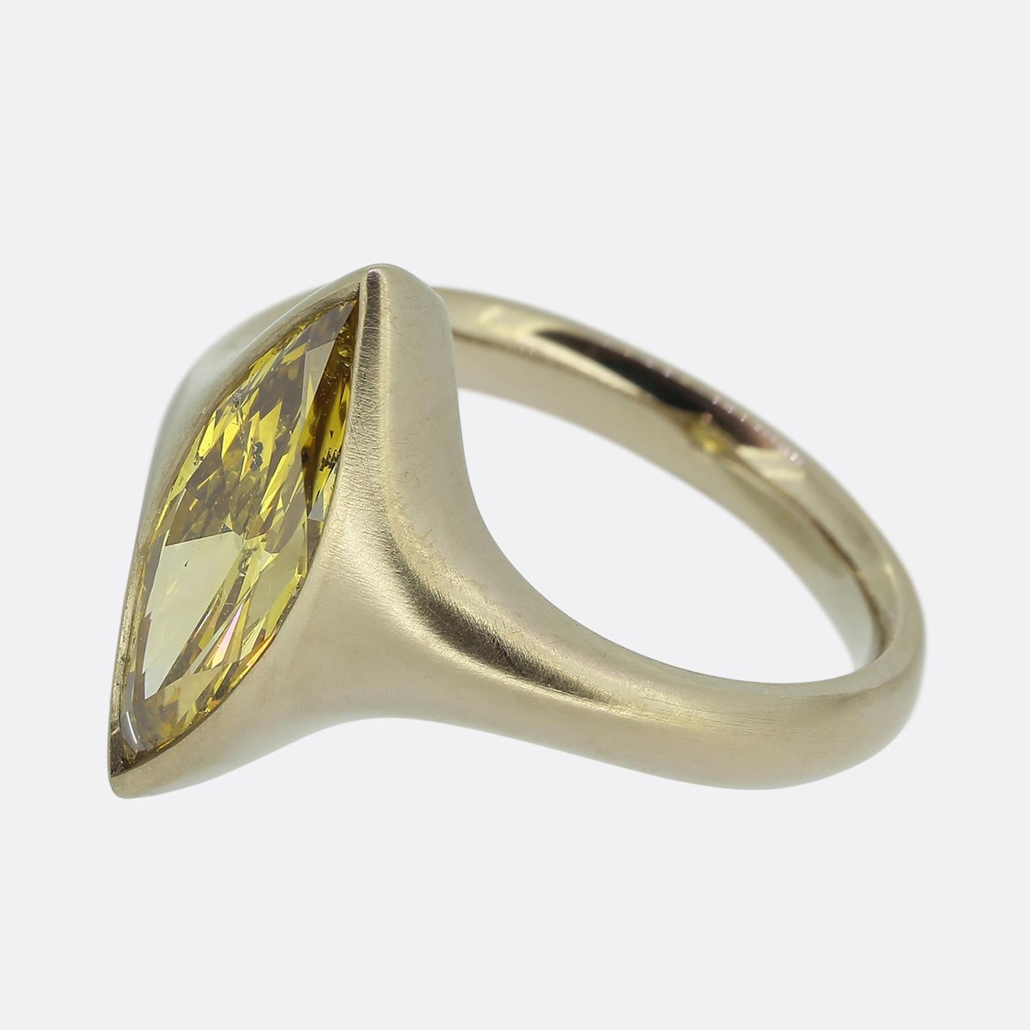 Here we have a striking 22ct gold diamond solitaire ring. At the centre of the face we find a single vibrant fancy orange yellow marquise-cut diamond mounted in a sleek bezel setting. The stone's elongated shape is accentuated by the smooth brushed