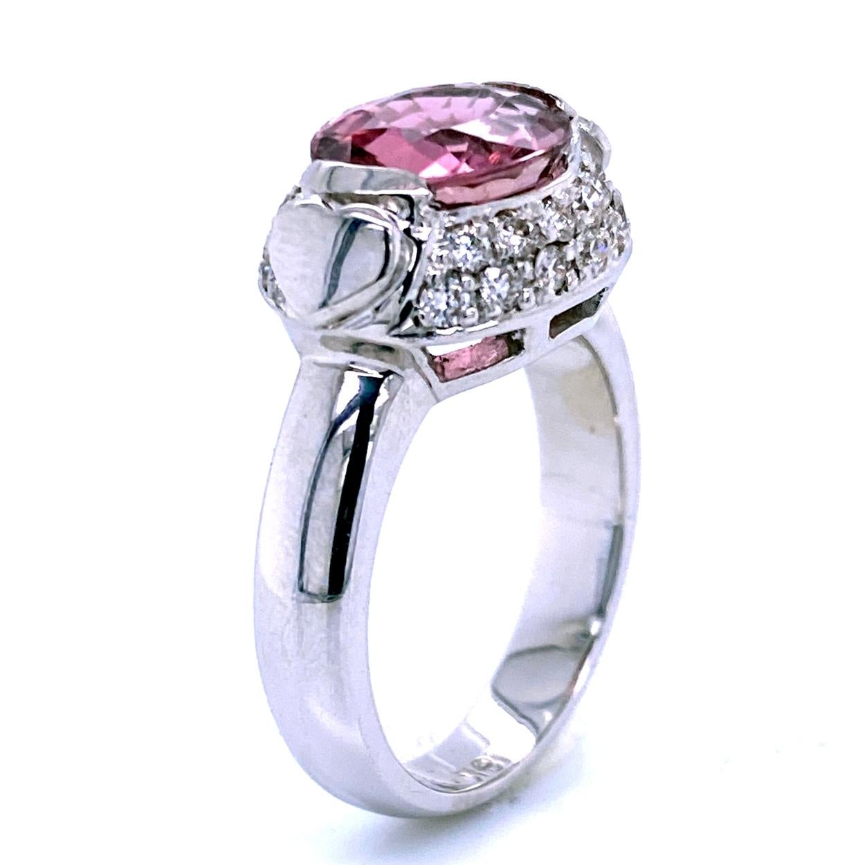 A beautiful color 2.65 Ct Oval shaped Pink Tourmaline Bezel set in the center of an 18K Pave set Diamond Engagement Ring. 

Details:
Center Stone: 2.95 carat Oval Pink Tourmaline - 10.5x8.5 mm
Side Stone Diamonds: 
26 pieces 1.5 mm VS2-SI1 Clarity,