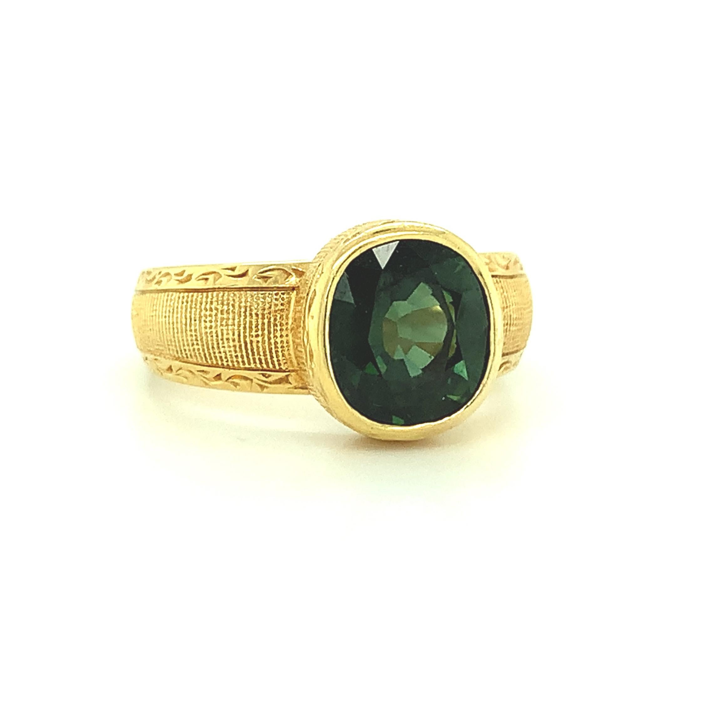 This handsome ring features a bright, 2.66 carat cushion cut green sapphire that has been set in a handmade 18k yellow gold bezel. The sapphire has a beautiful slightly bluish green color and sits low enough on the finger to make this a perfect ring