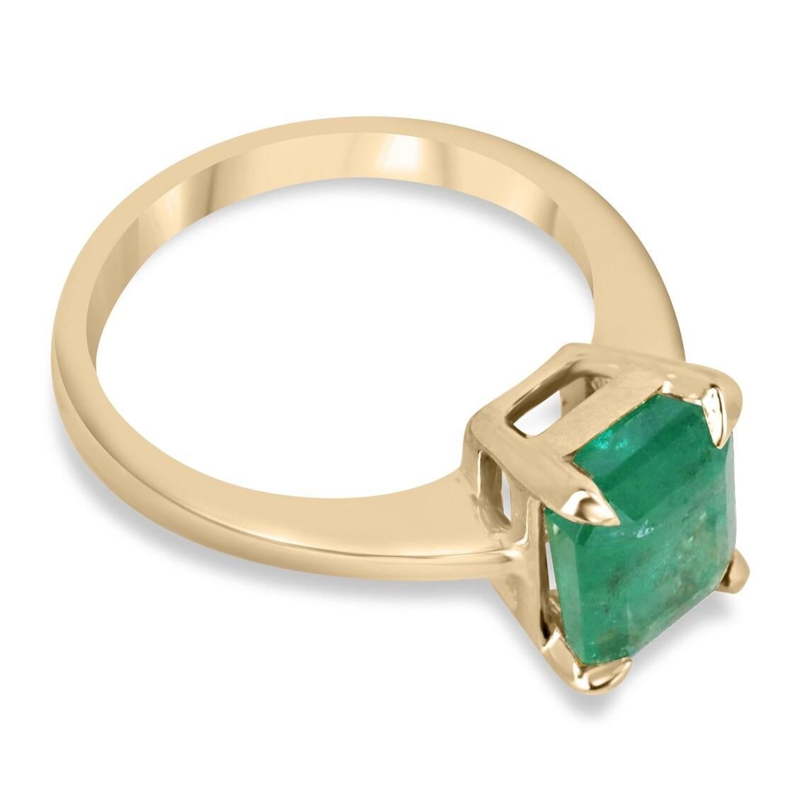 This stunning engagement ring features a natural emerald cut emerald with a weight of 2.66 carats set in a claw four-prong design. The emerald's rich green color adds a touch of elegance and sophistication to the 14K gold band. This solitaire