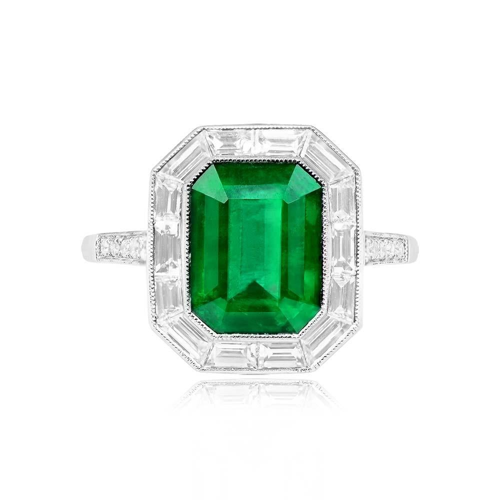 Captivating halo engagement ring showcasing a 2.66-carat emerald-cut natural green emerald, bezel-set in platinum. The emerald is surrounded by a halo of baguette-cut diamonds, totaling 0.73 carats, with additional round brilliant-cut diamonds