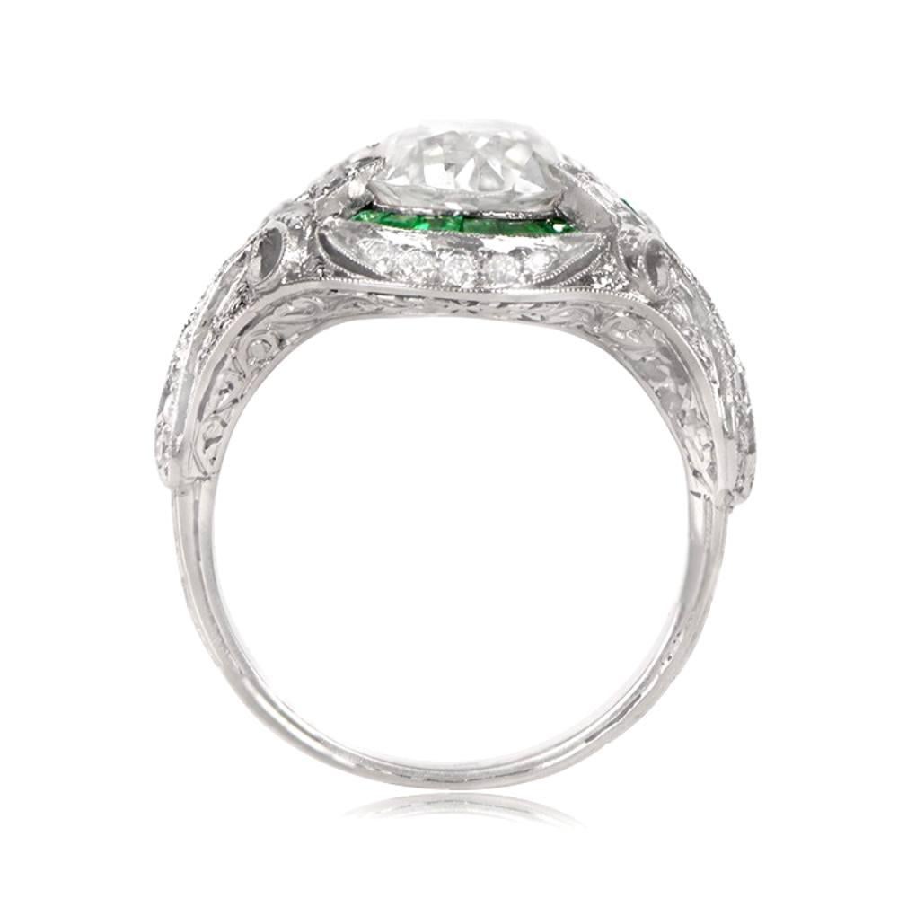 This Art Deco style engagement ring features an antique old European cut diamond, accented with diamonds and milgrain. The ring also boasts a delicate halo of emeralds and bow motif filigree on the shoulders. The center diamond, cut during the Art