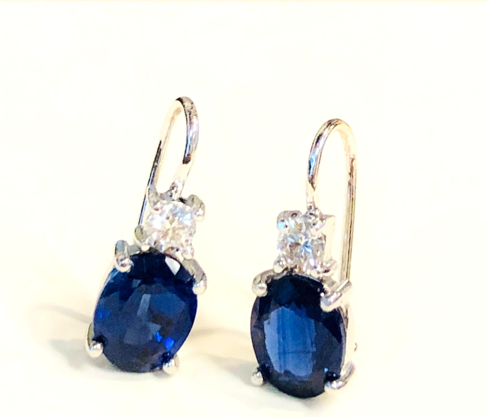 The classic pairing of blue sapphires and diamonds in these 18k white gold drop earrings is elegance personified! Royal blue sapphires ovals are accented by round white diamonds, creating perfect earrings that will complete any outfit, from casual