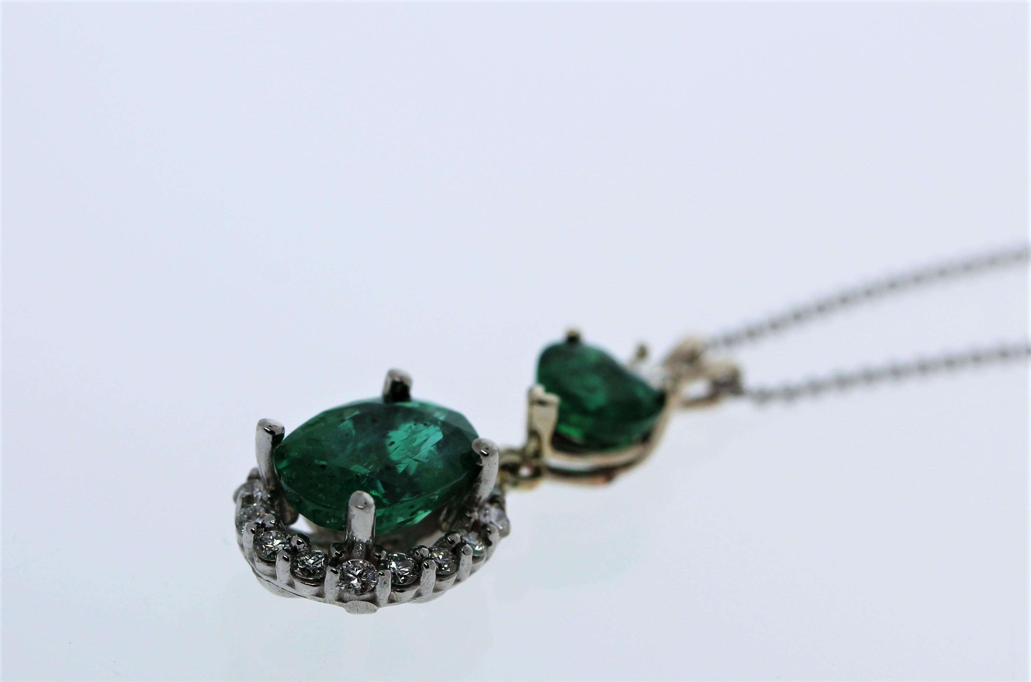 A gorgeous 14K white gold pendant that showcases two emeralds that total up to 2.67 carats. It also consists of 18 natural round diamonds that total up to 0.43 carats.