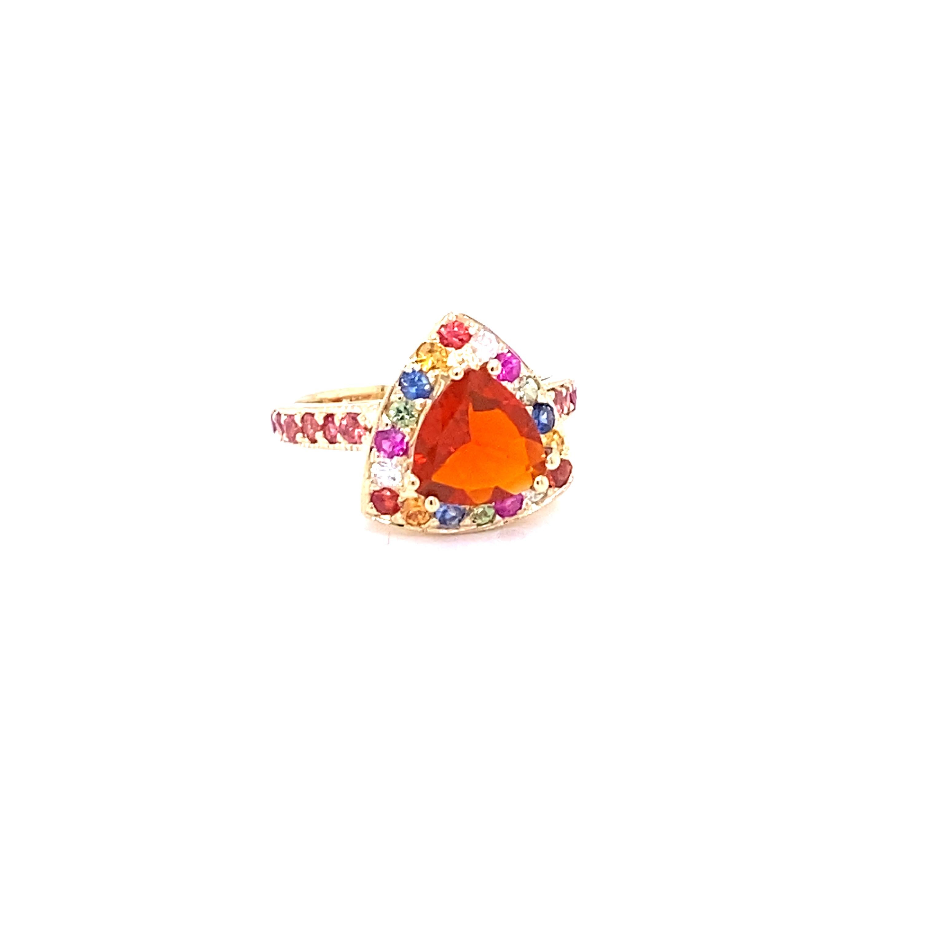 This Ring has a 1.35 Carat  Trillion Cut Fire Opal as its center stone and is beautifully surrounded by 30 Multi-Colored Sapphires that weigh 1.33 Carats.
The Total Carat Weight of this ring is 2.68 Carats. 
This Ring is casted in 14K Yellow Gold
