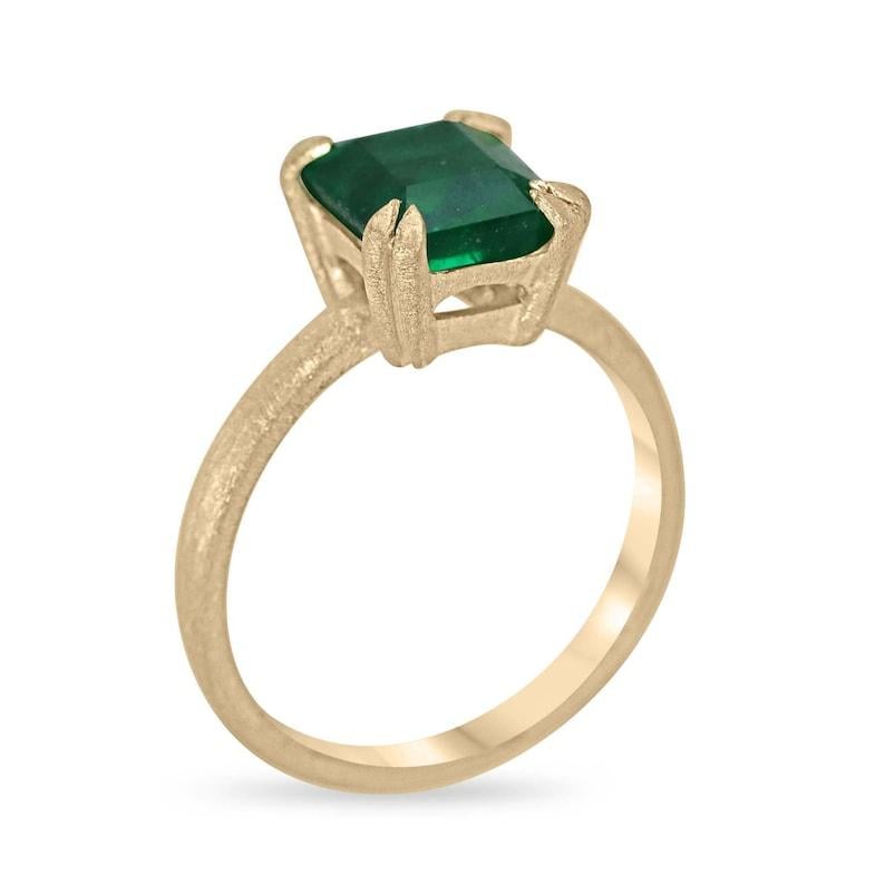 Experience the epitome of elegance with our Solitaire Emerald Cut Emerald Ring. A magnificent 2.68-carat emerald, sourced from Zambia, takes center stage in a north-to-south orientation, held securely by a solitaire double claw prong setting that
