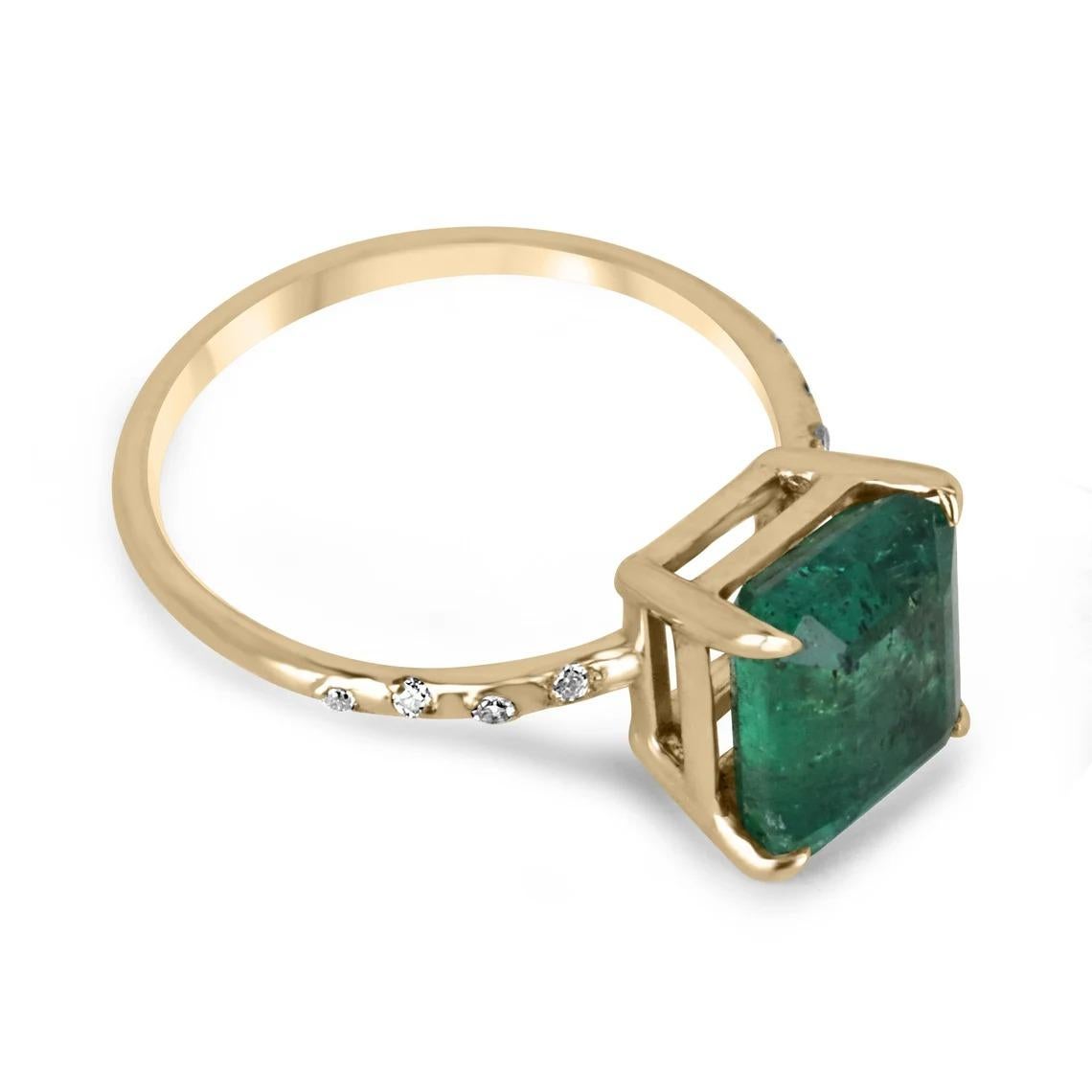Displayed is a modern emerald and diamond solitaire engagement ring/right-hand ring in 14K yellow gold. This gorgeous solitaire ring carries a 2.60-carat emerald in a four-prong setting. Fully faceted, this gemstone showcases excellent shine. The