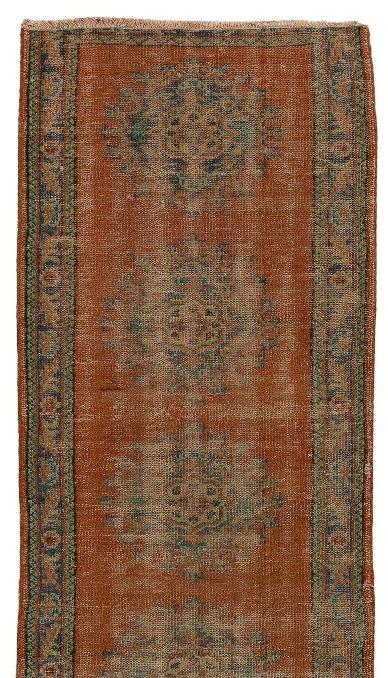 Türkischer Vintage-Läufer mit einem Muster aus mehreren Medaillons in Schieferblau und Smaragdgrün auf einem einfarbigen Feld in Rostrot sowie einer schieferblauen Bordüre. Er wurde in den 1960er Jahren in der Türkei handgeknüpft, mit niedrigem
