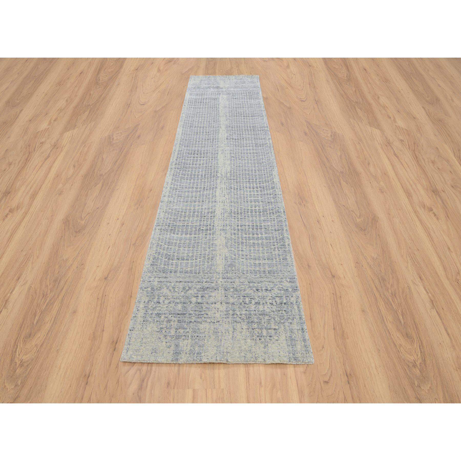 Se trata de una auténtica alfombra oriental, única en su género, gris, tono sobre tono, de diseño transicional borrado, tejida a mano en jacquard, de lana y seda vegetal. Ha sido tejida durante meses y meses con técnicas artesanales de tejido
