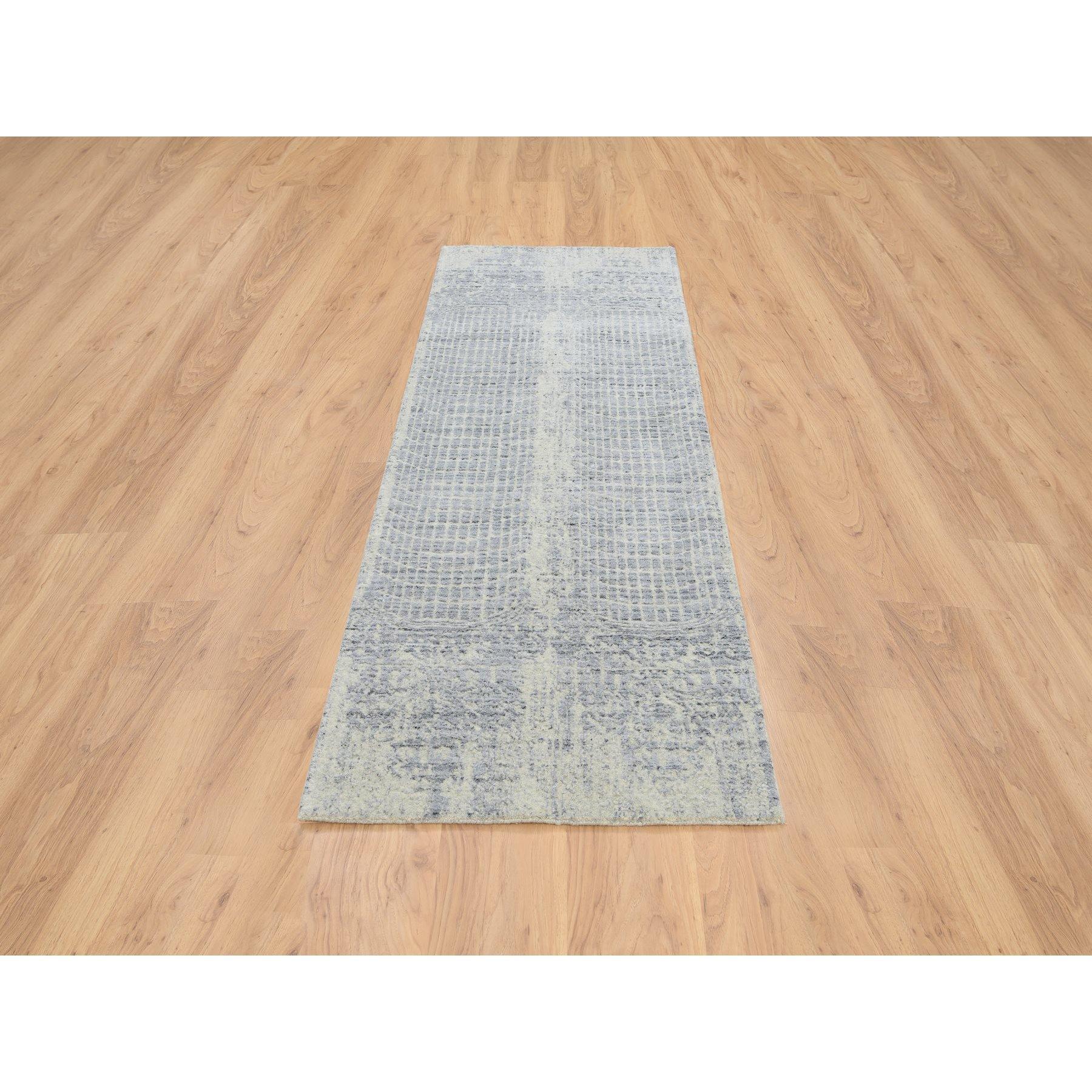 Se trata de una auténtica alfombra de calle oriental, gris, tono sobre tono, de diseño transicional borrado, tejida a mano en jacquard, de lana y seda vegetal. Ha sido tejida durante meses y meses con técnicas artesanales de tejido centenarias por