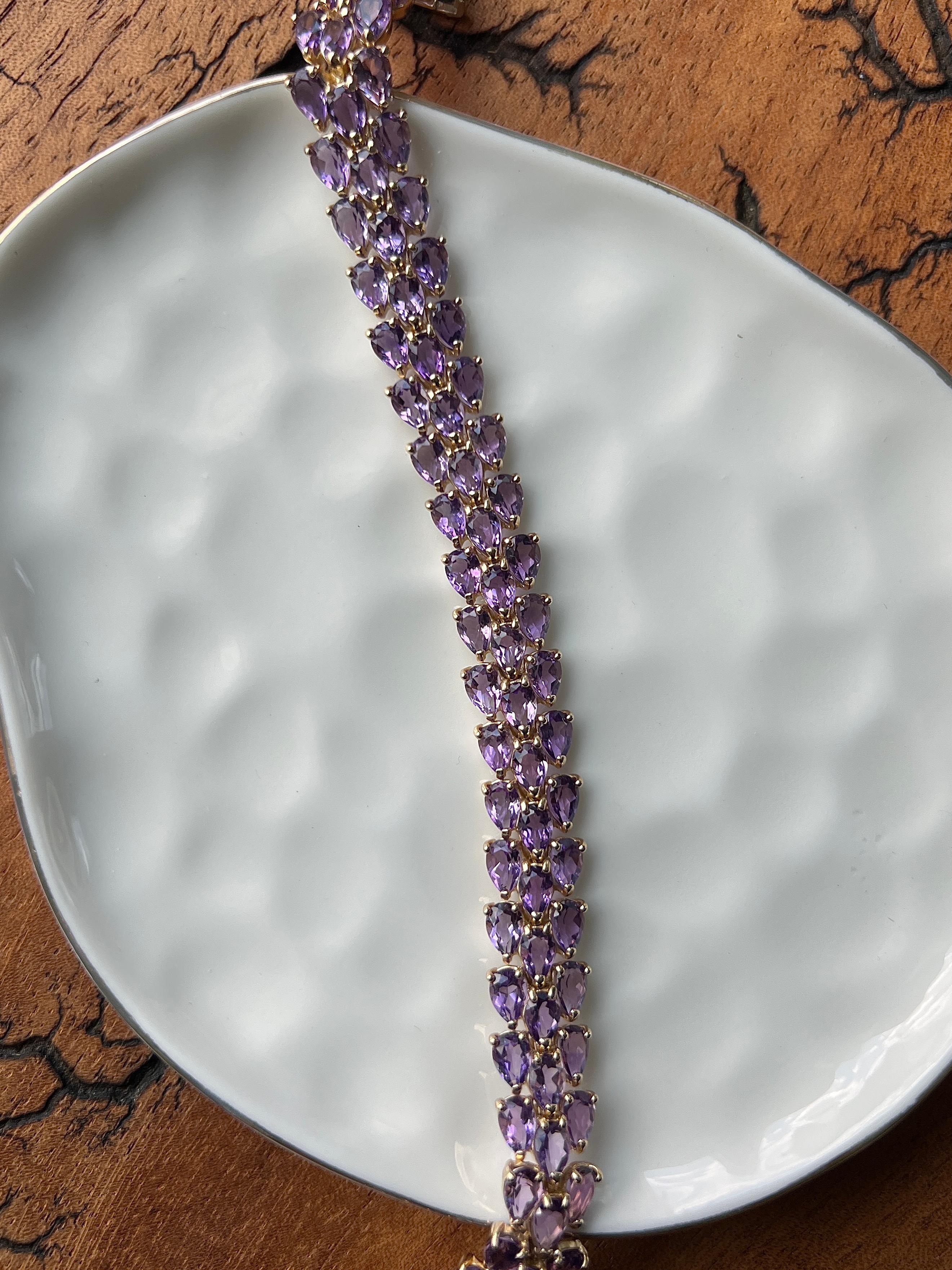 Un bracelet contemporain en or jaune 14 carats serti de quatre-vingt-dix améthystes en forme de poire totalisant environ 27,00 carats. Les pierres précieuses d'un violet éclatant sont disposées en deux rangées rapprochées, créant une ligne