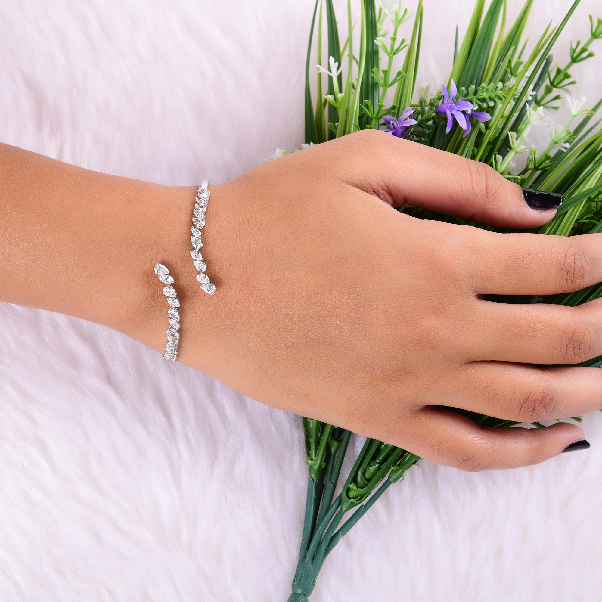 Questo bracciale da polso con diamanti da 2,7 carati SI/H in oro bianco 14 carati presenta le seguenti caratteristiche
un polsino aperto. I punti focali sono diversi diamanti a forma di pera su ciascuna estremità dell'apertura del bypass.
I diamanti